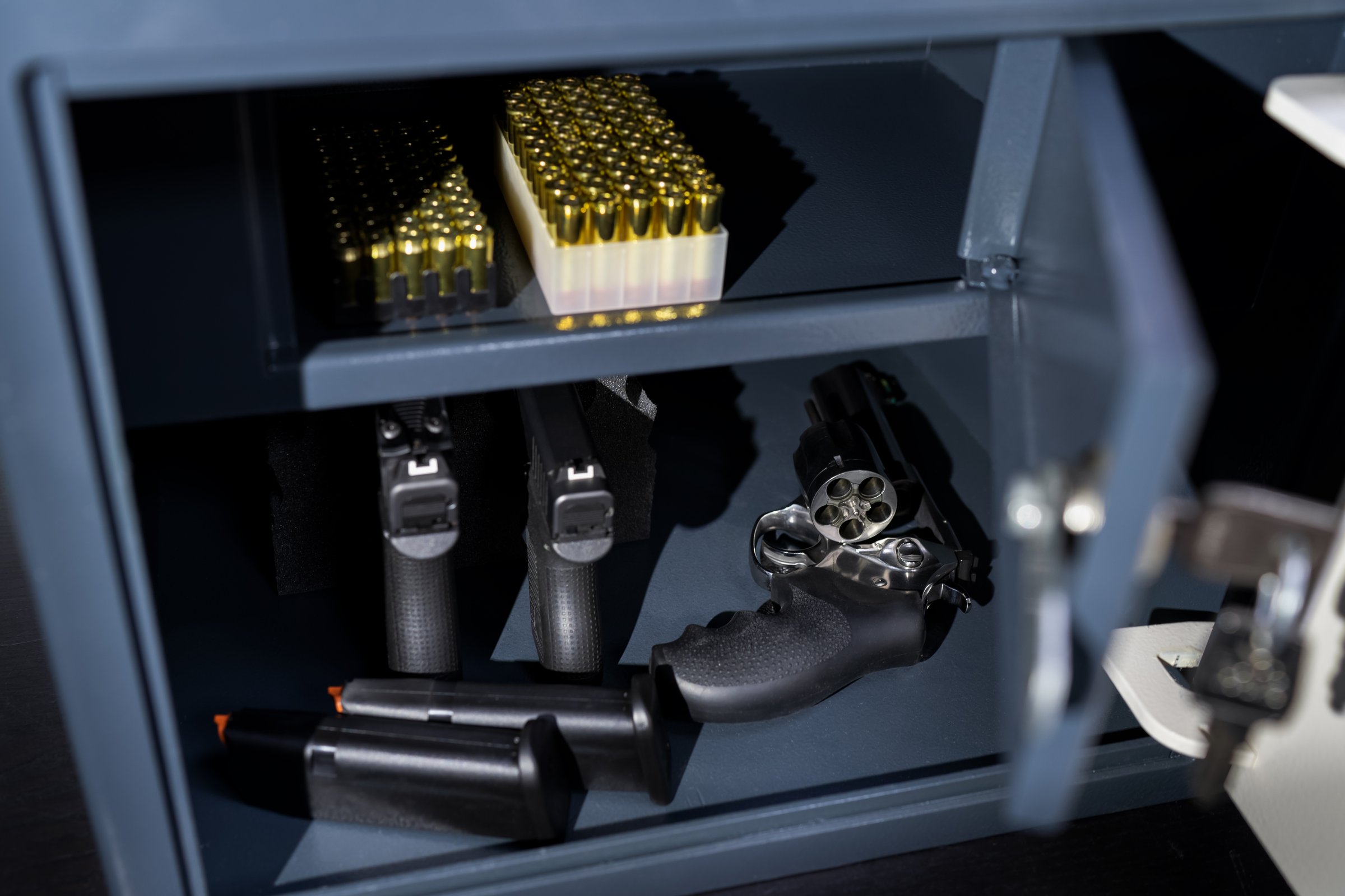 Pistols, revolver and cartridges in a gun safe, close-up photo.