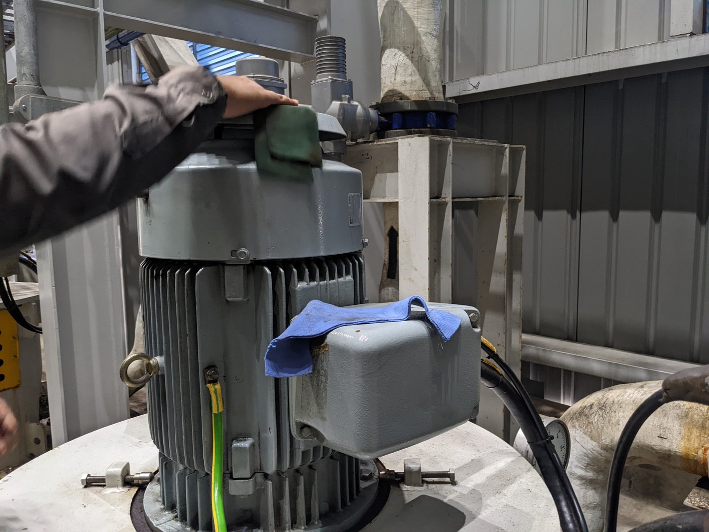 A closeup of an industrial motor being inspected or maintained by a worker in a factory setting.