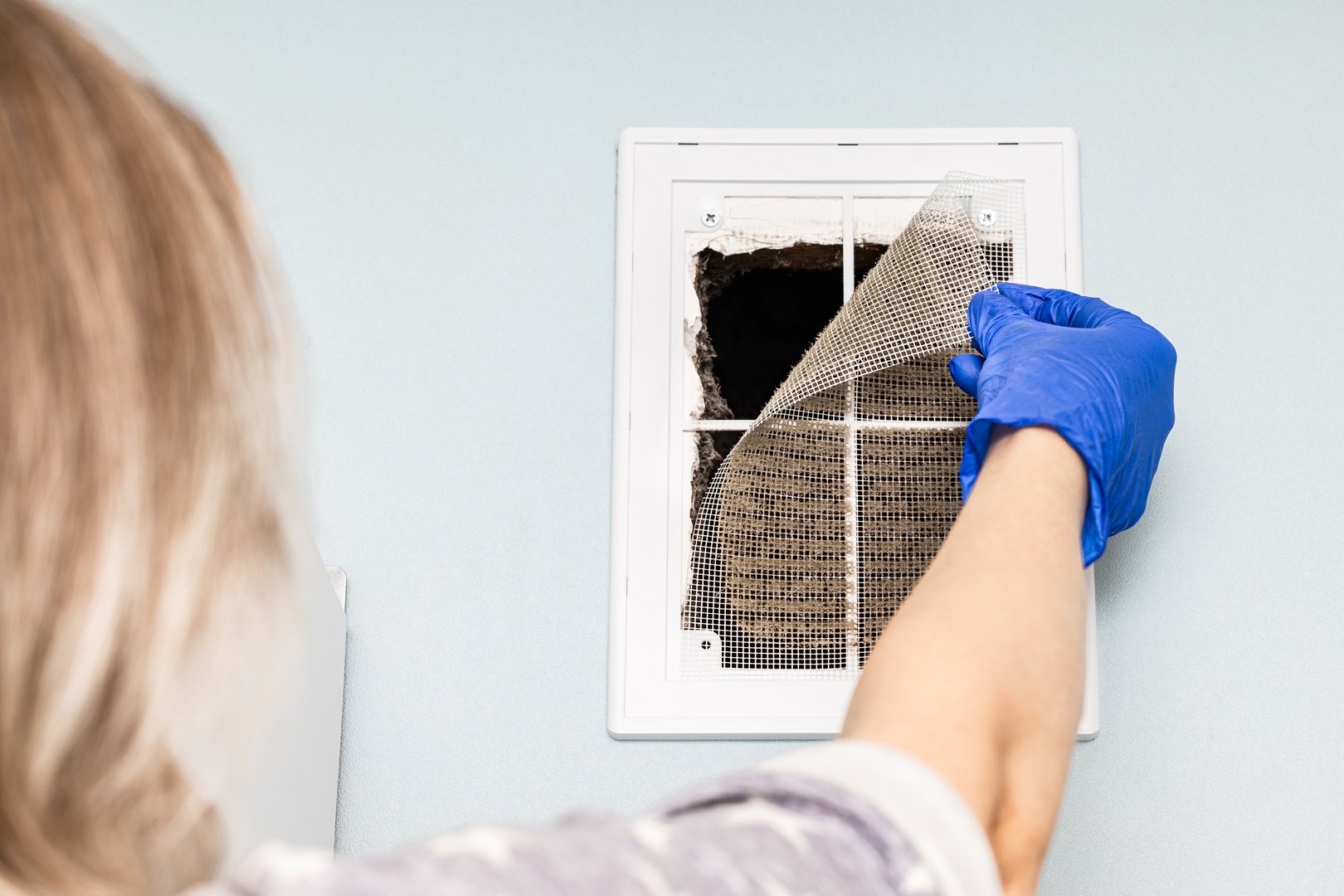 man cleaning dirty ventilation grille in house. dirty ventilation grill. hand removes ventilation grille. dirty ventilation filter