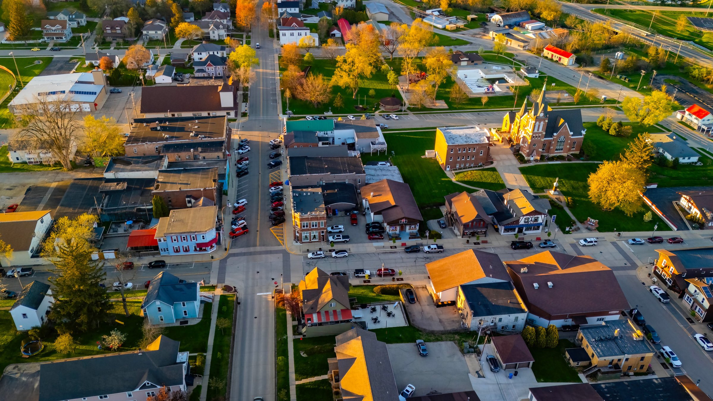 New Glarus Wisconsin at sunset showing city buildings, rooftops, and the Swiss United Church of Christ in golden light.