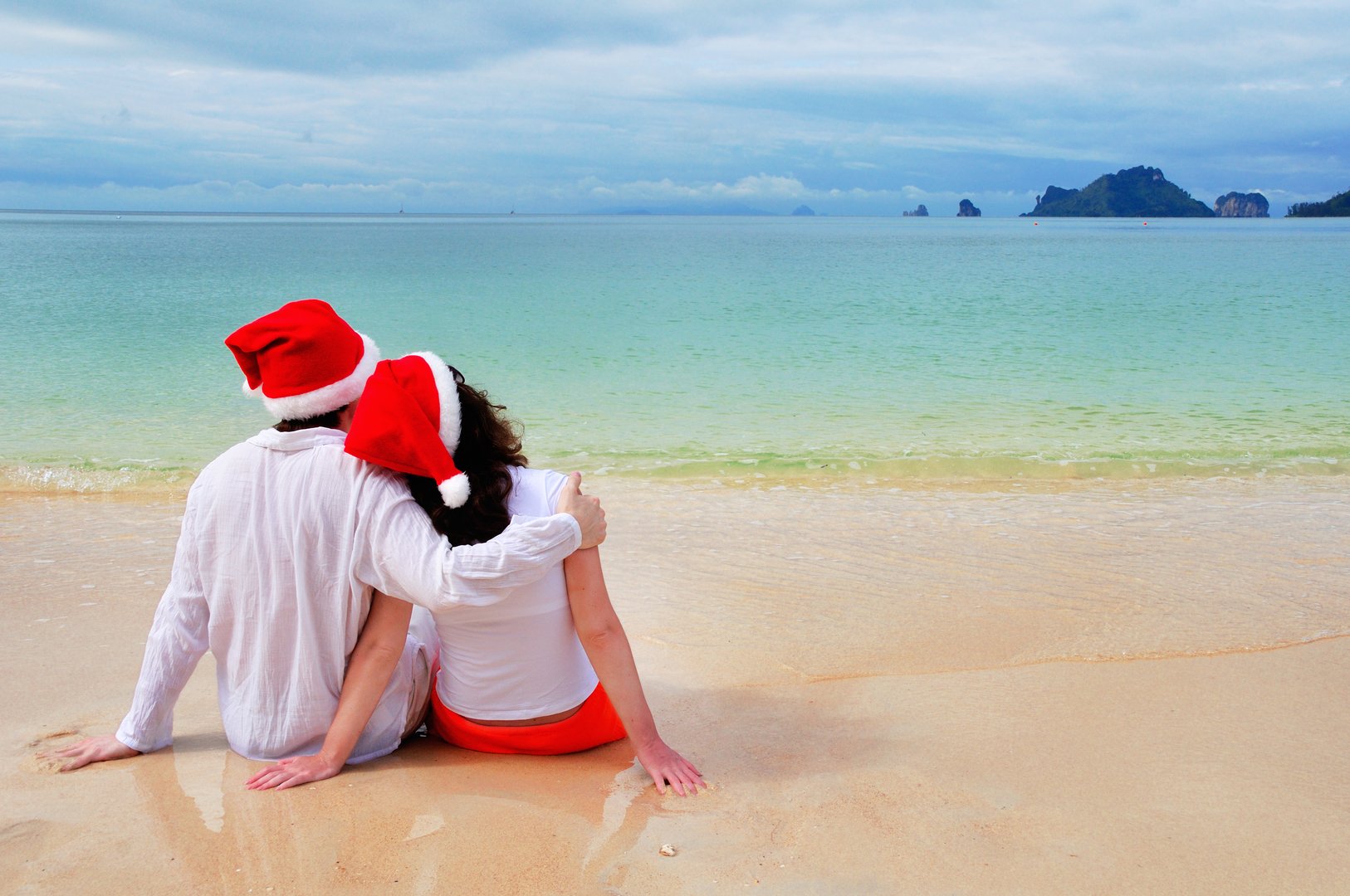 Christmas and New Year holiday concept, romantic couple in santa hats on tropical beach on vacation