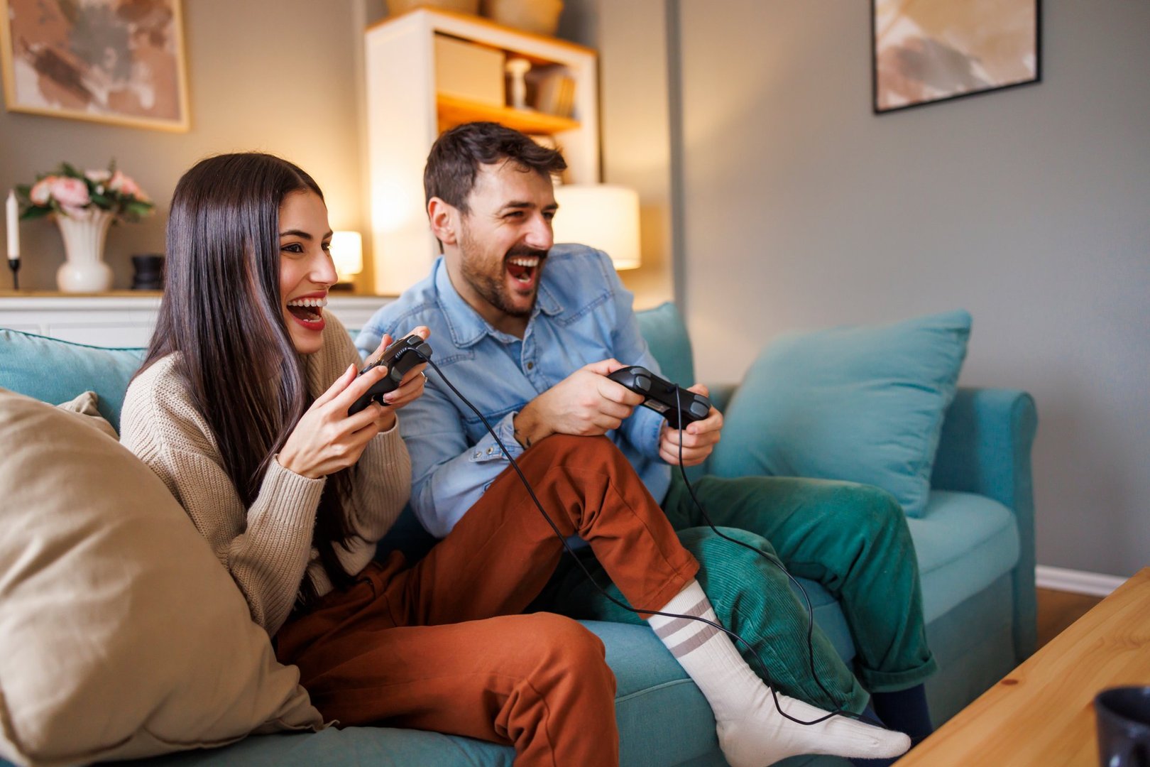 Beautiful young couple in love having fun playing video games while relaxing and enjoying spending leisure time together at home