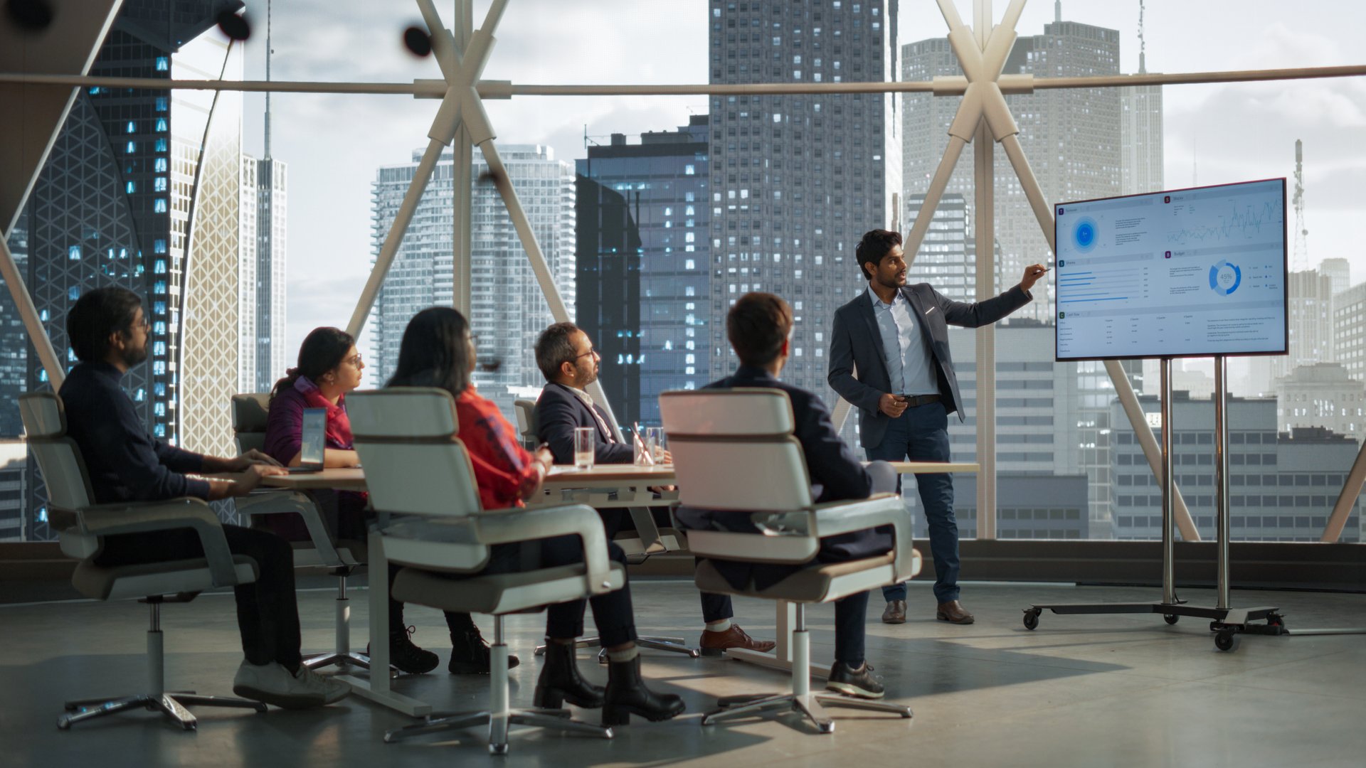 Diverse Indian Office Conference Room: Young South Asian CEO Makes a Presentation for Entrepreneurs, Talking, Using TV with Infographics and Statistics. Businesspeople Talk About an Ecommerce Startup