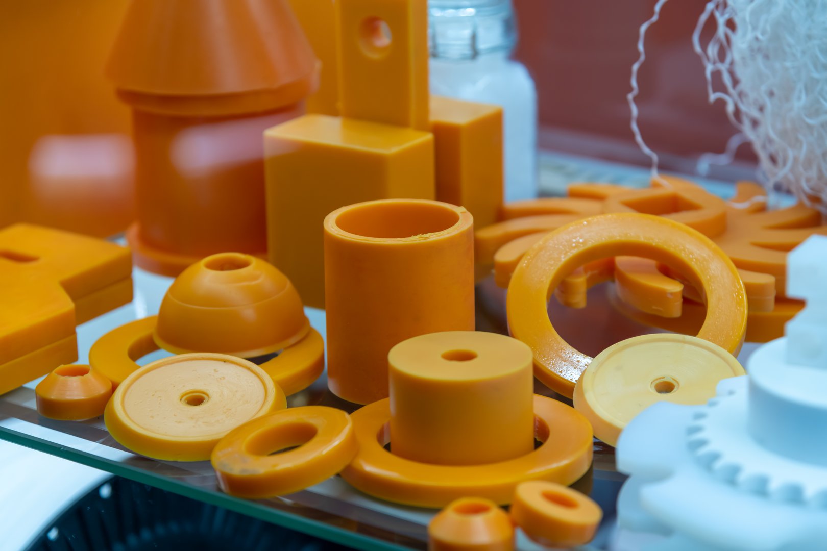 An array of orange plastic parts arranged attractively in a modern display case highlights advancements in manufacturing techniques and material design.