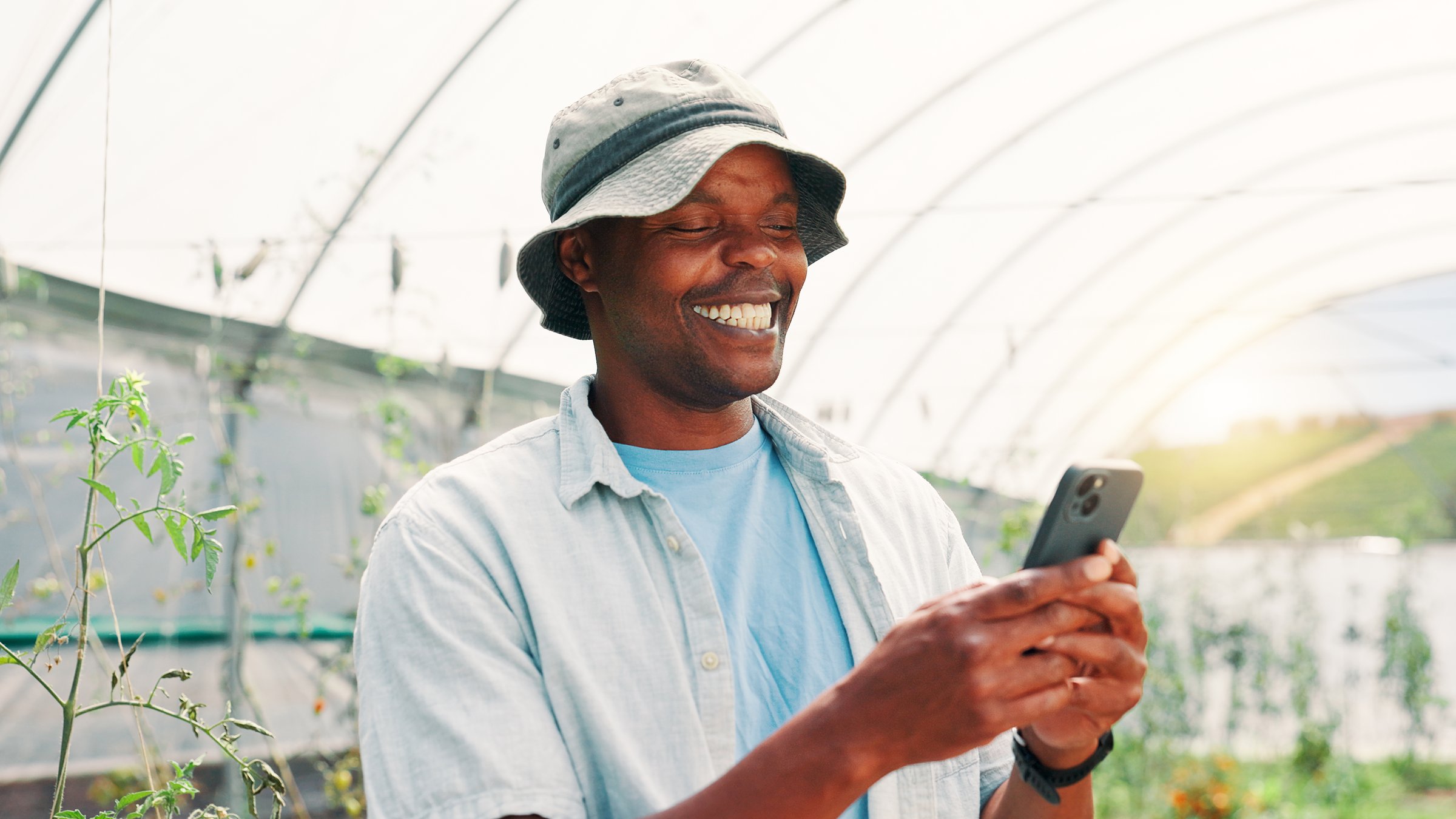 African farmer smiling while using smartphone for agricultural information