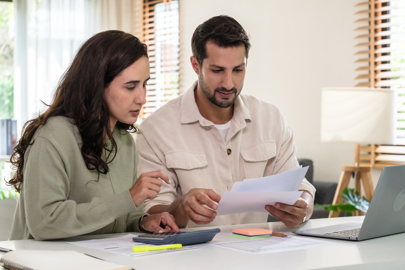 Couple budgeting and calculating tax with laptop at home, managing finance and planning for longterm investment