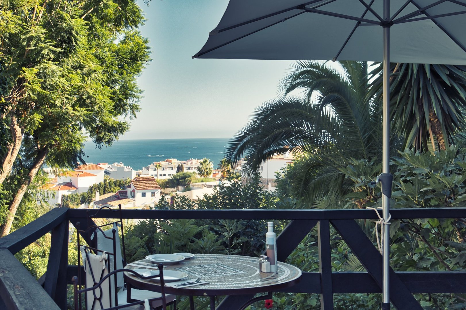 Fuengirola, Spain - August 19, 2022. Typical landscape of Andalusia, with its white villages in southern Spain. Palm trees and acacias are visible in the foreground. The Mediterranean Sea is visible in the background.