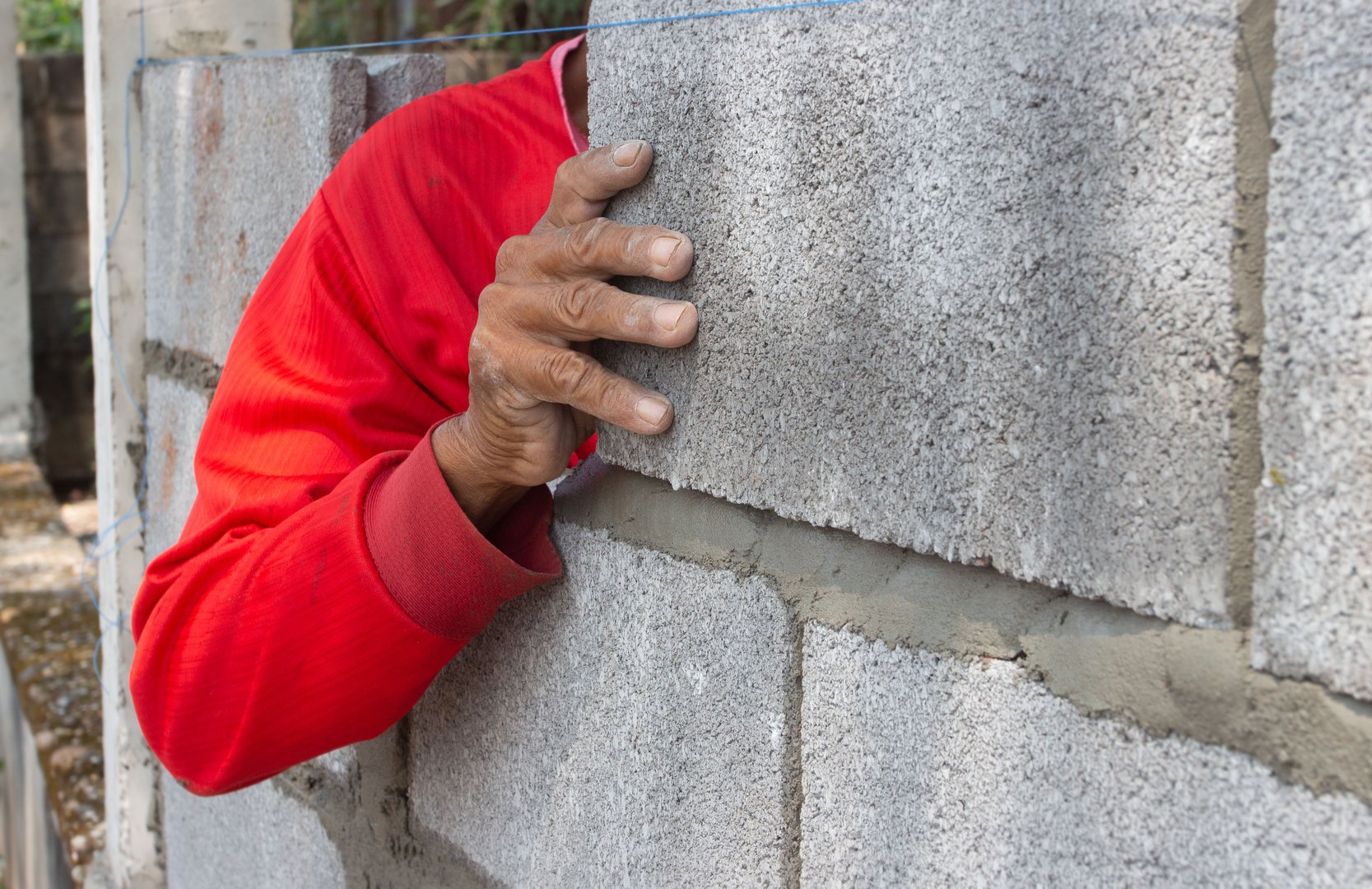 masonry worker make concrete wall by cement block and plaster at construction site. building cement walls with brick blocks.