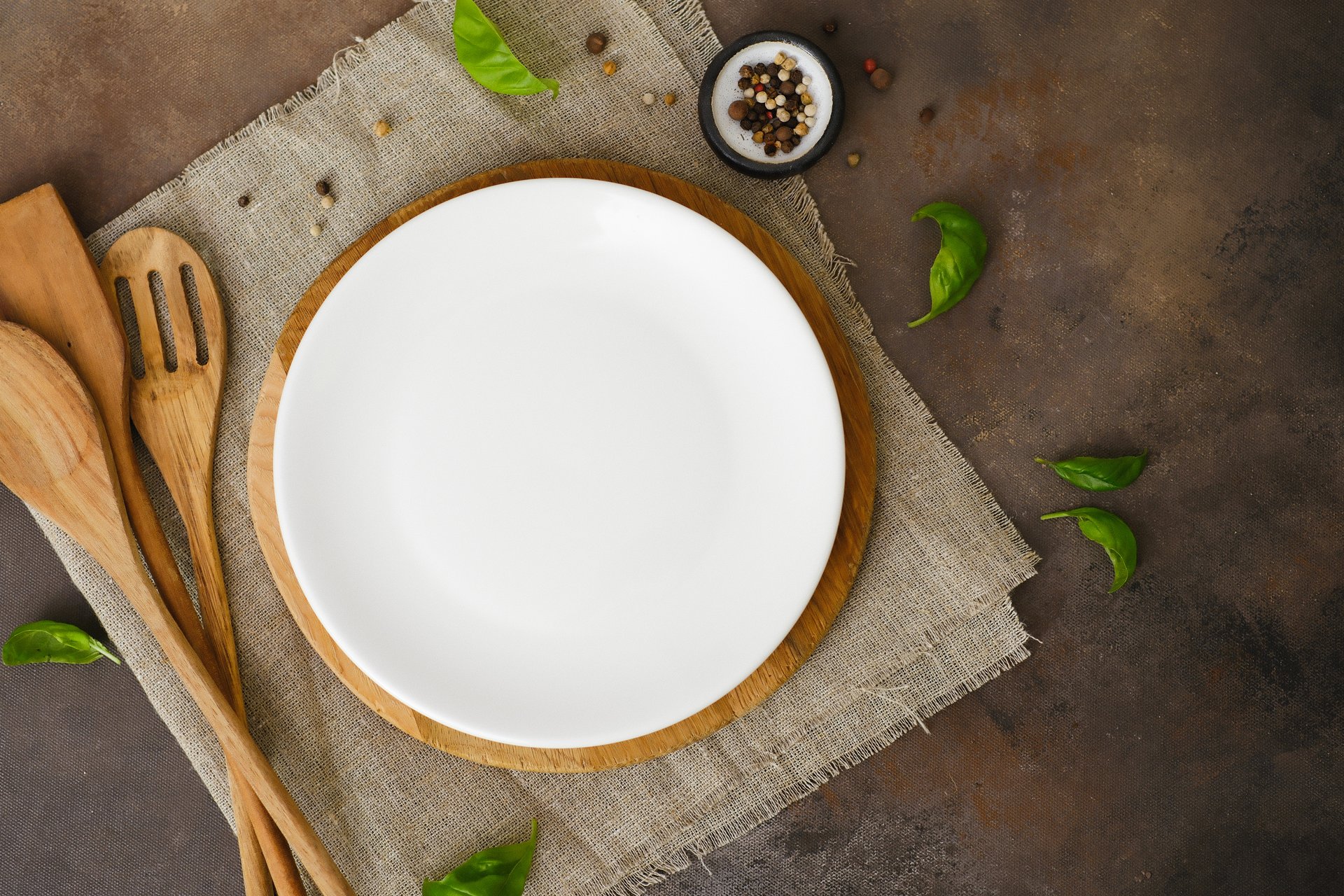 Food background decoration: wooden, black plate, spatulas, brown napkin on brown background. High quality photo