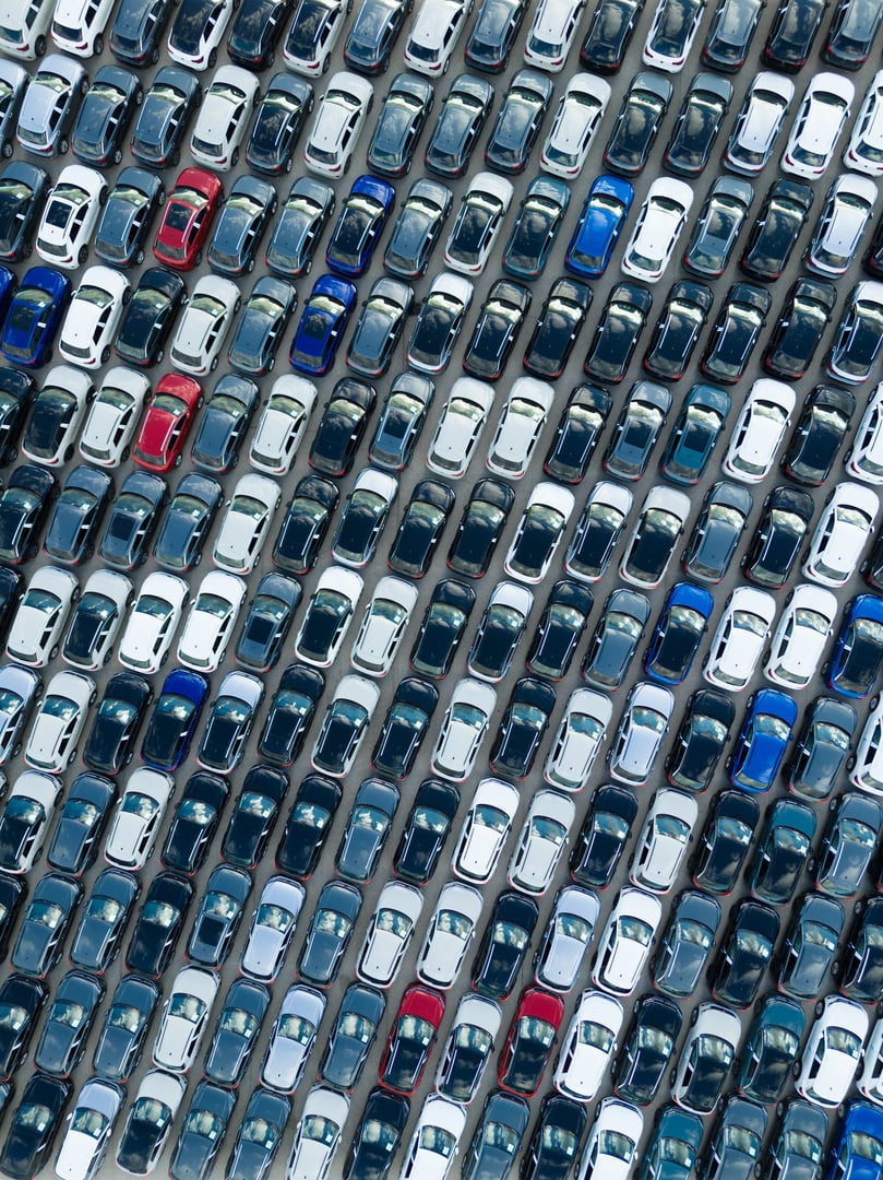 New Cars on Large Parking Lot in Port Ready for Distribution to Dealer. Automotive Industry Business. Aerial Overhead Top-Down Drone Shot