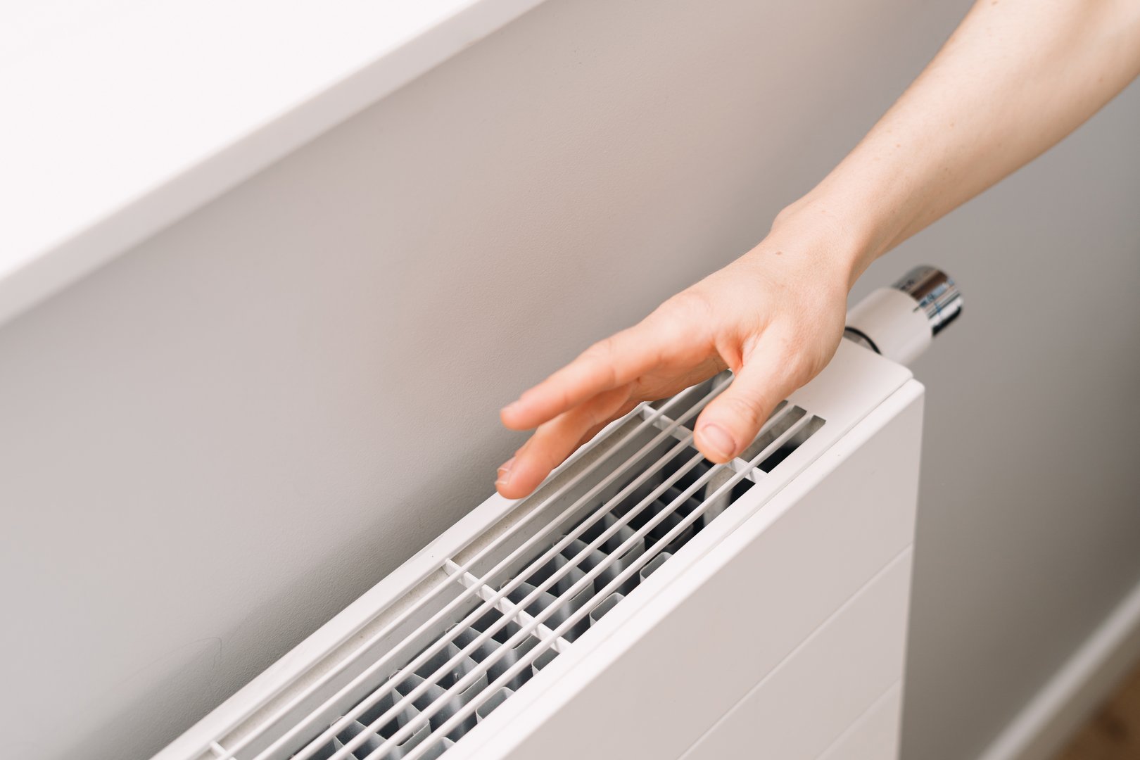A hand checking warmth of a new electric heater in a cozy apartment