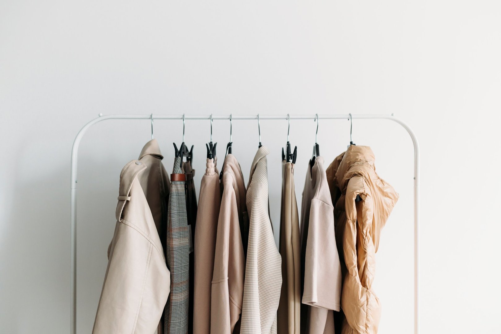 Spring capsule clothes of beige color palette on a rack over wwhite background. Closeup