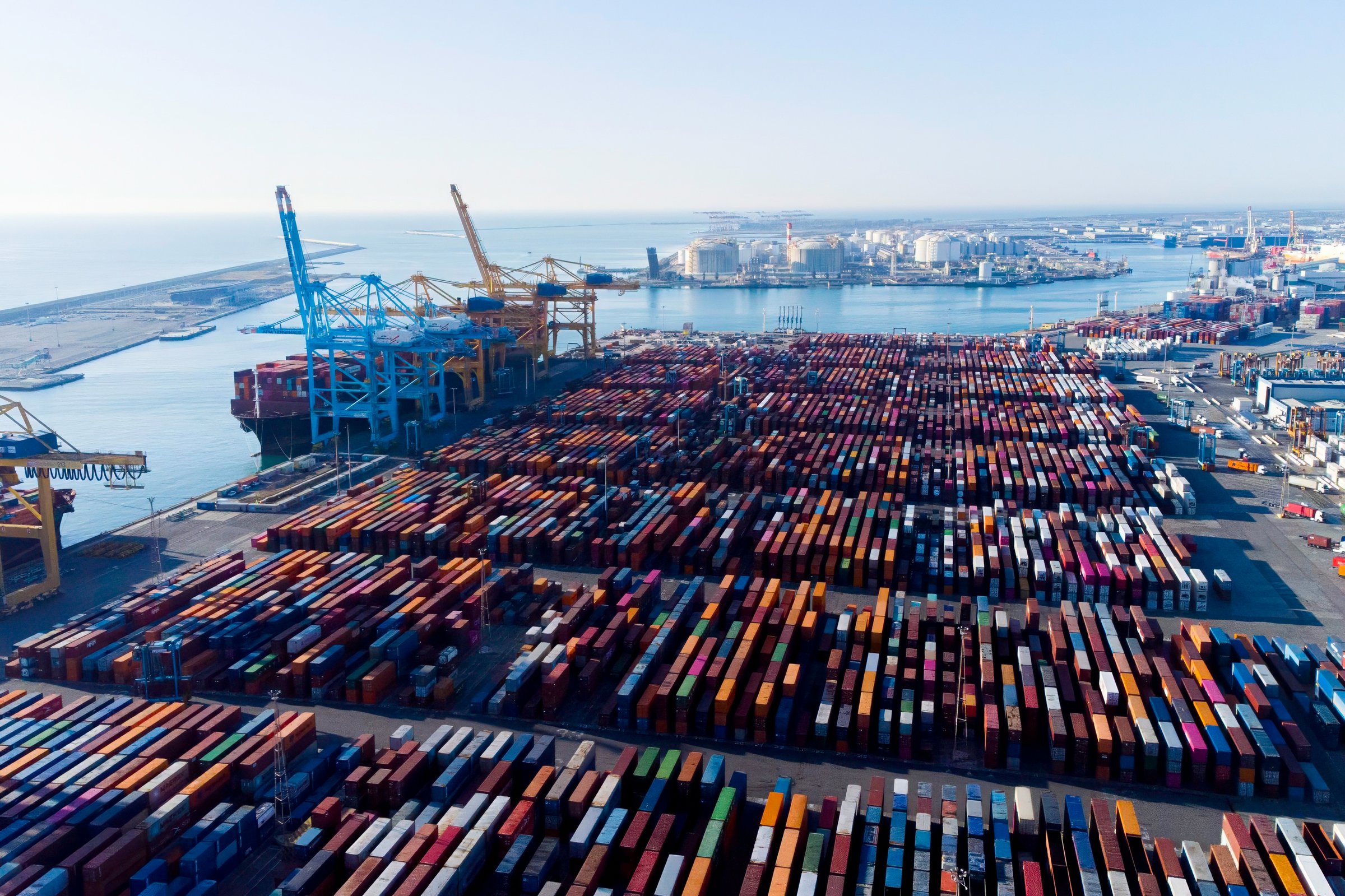 Aerial view of shipping containers and cargo ships in the sea port of Barcelona in Spain, Europe. Concept of sea and maritime trade and trade war due to tariffs. Commercial hub