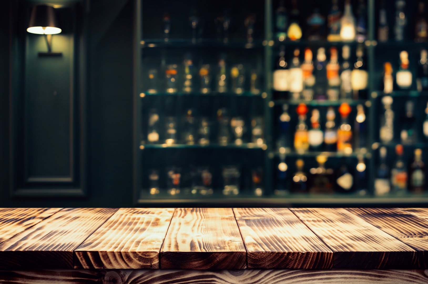 Real photographs material of rustic wooden bar countertop with a warm, ambient background of blurred bottles and shelves.