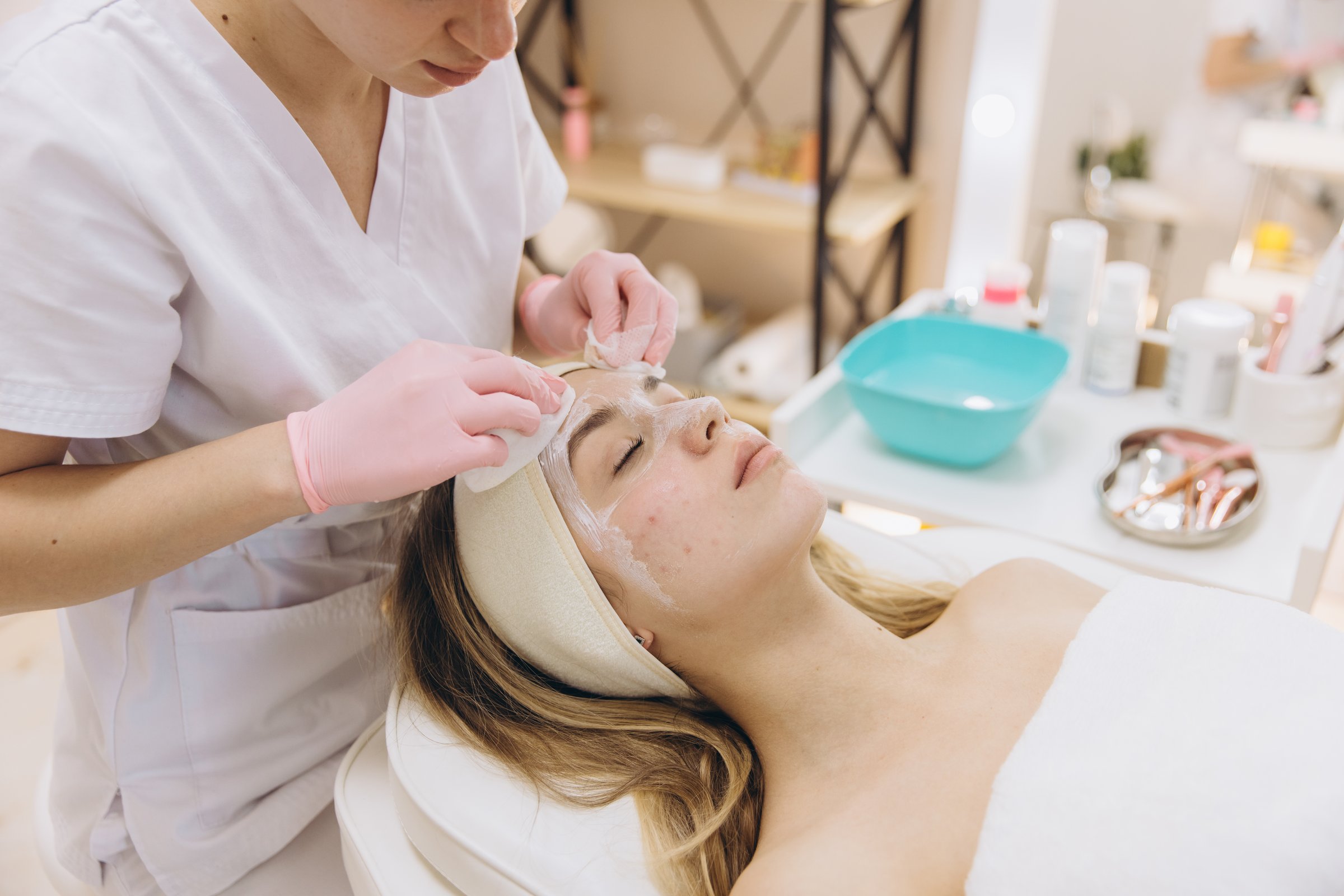 Professional beautician performing skin rejuvenation facial, carefully working on relaxed client within elegant beauty salon setting