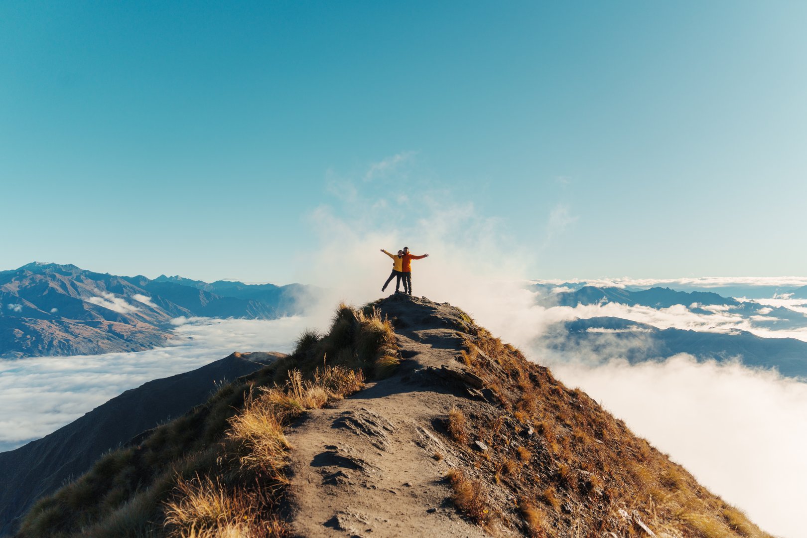 Achievement couple hiker standing on Roys Peak summit mountain with foggy between Wanaka and Glendhu Bay in the morning at New Zealand