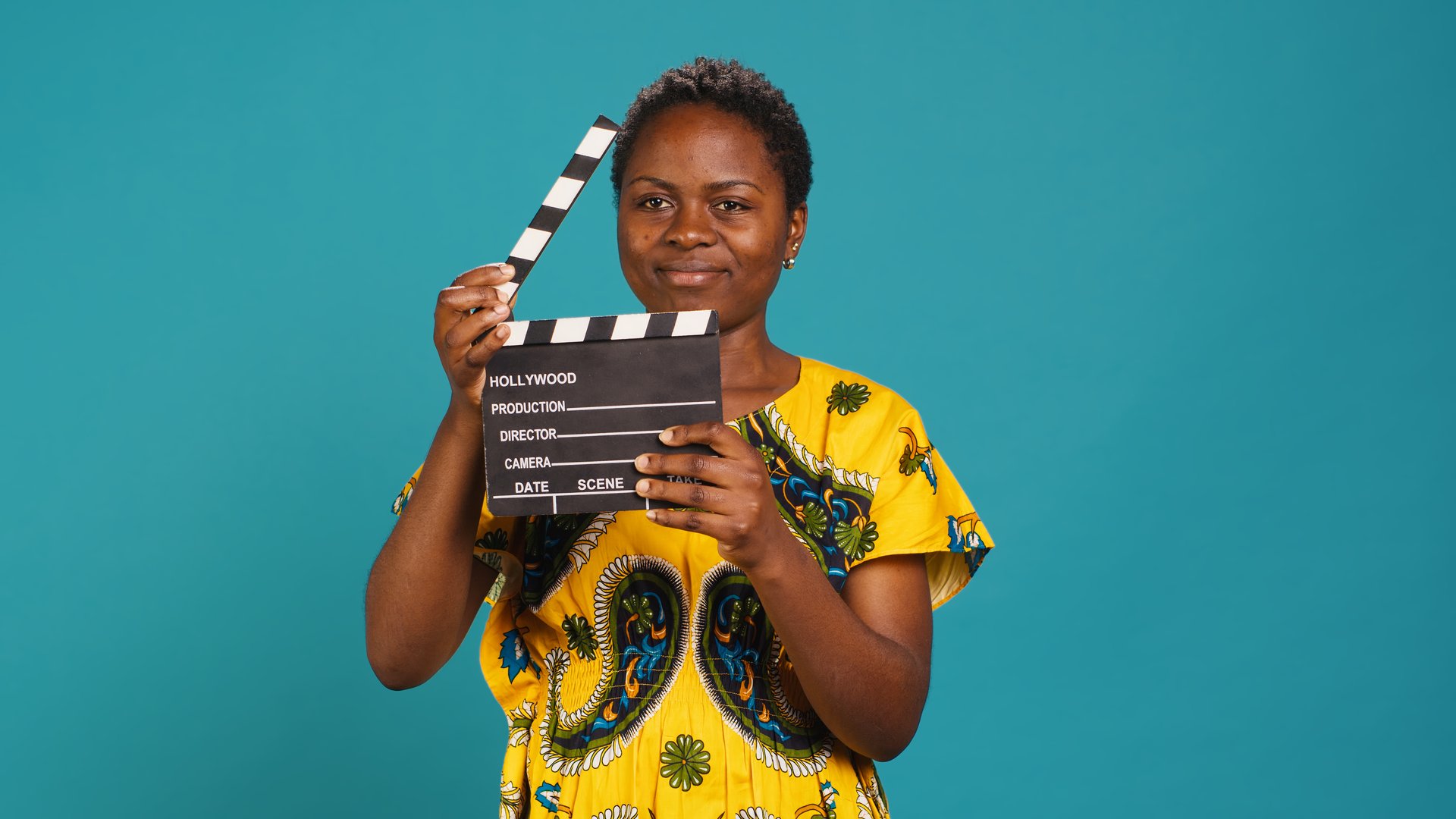 Female film producer using a clapperboard to say action in movie industry and cinematography. Skilled filmmaker woman cutting a scene with filming slate, video production. Camera A.