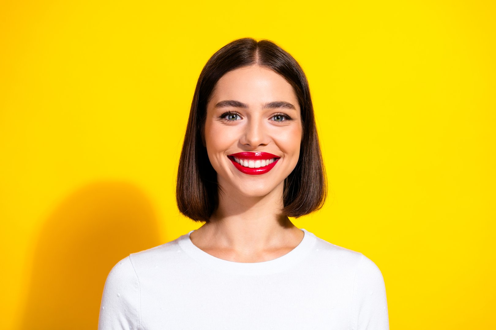 A smiling young brunette model wearing a white shirt