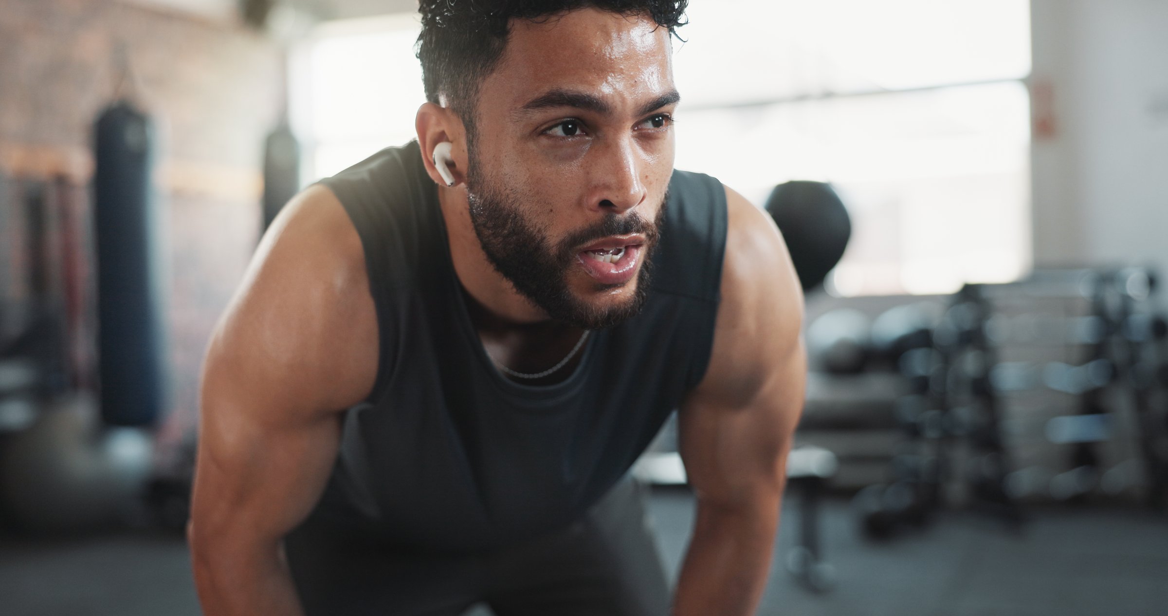 Man, sweating and tired in recovery for workout, intense exercise and wellness with fatigue. Male person, breathing and exhausted as athlete for health, challenge or training in fitness, sport or gym