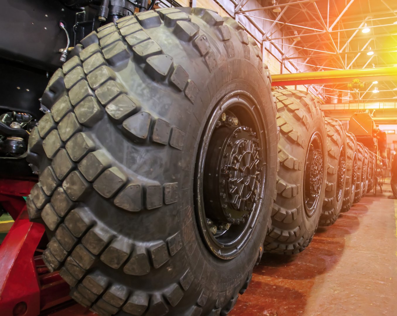 Large, rugged tires arranged in warehouse for construction and heavy machinery