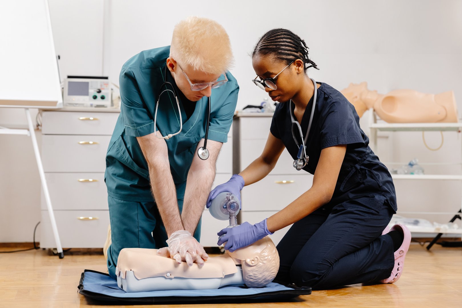 Two medical professionals practice CPR on a training mannequin, demonstrating proper technique and teamwork.