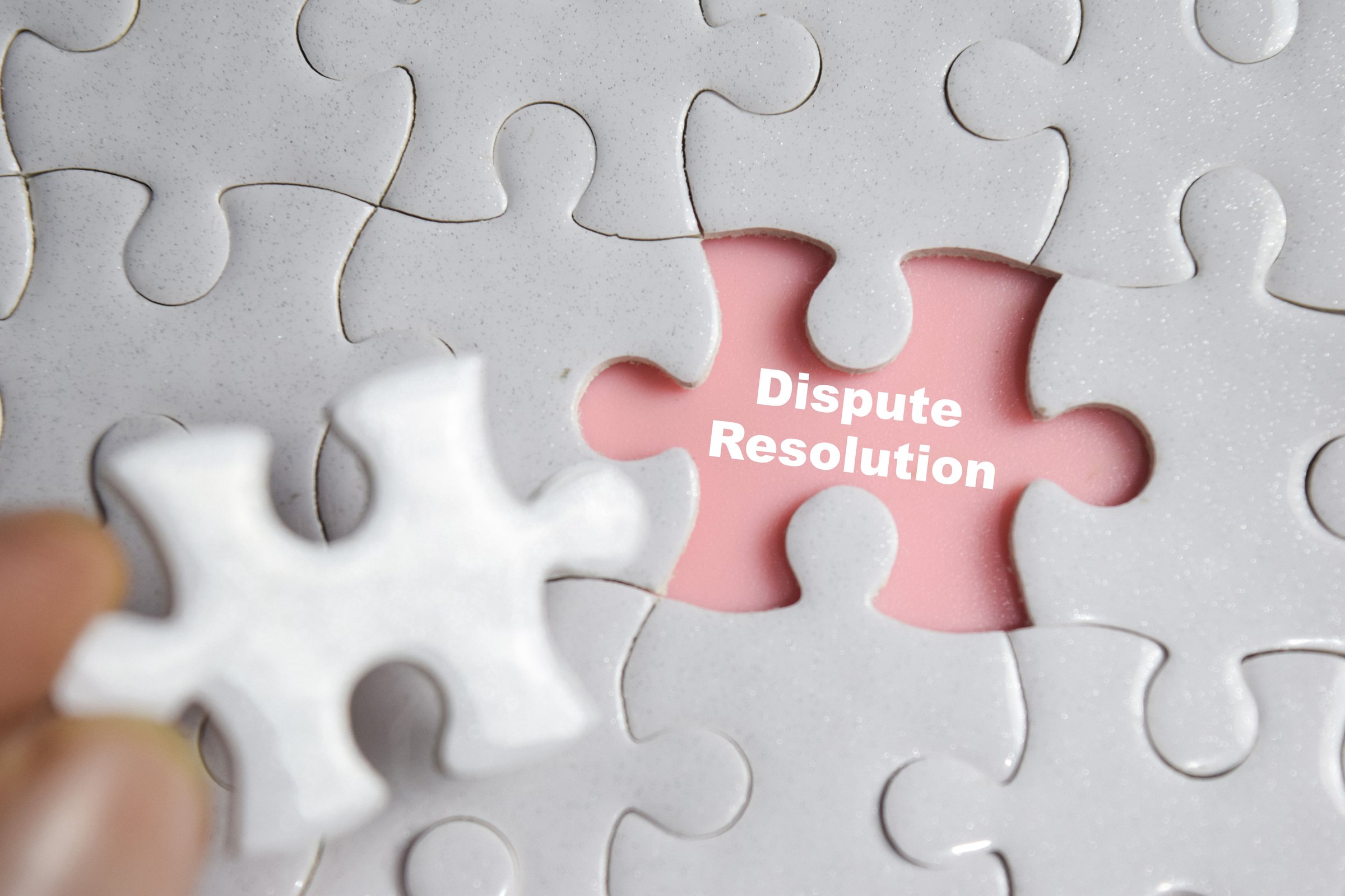 Hand holding piece of jigsaw puzzle with word Dispute Resolution. Business and finance concept