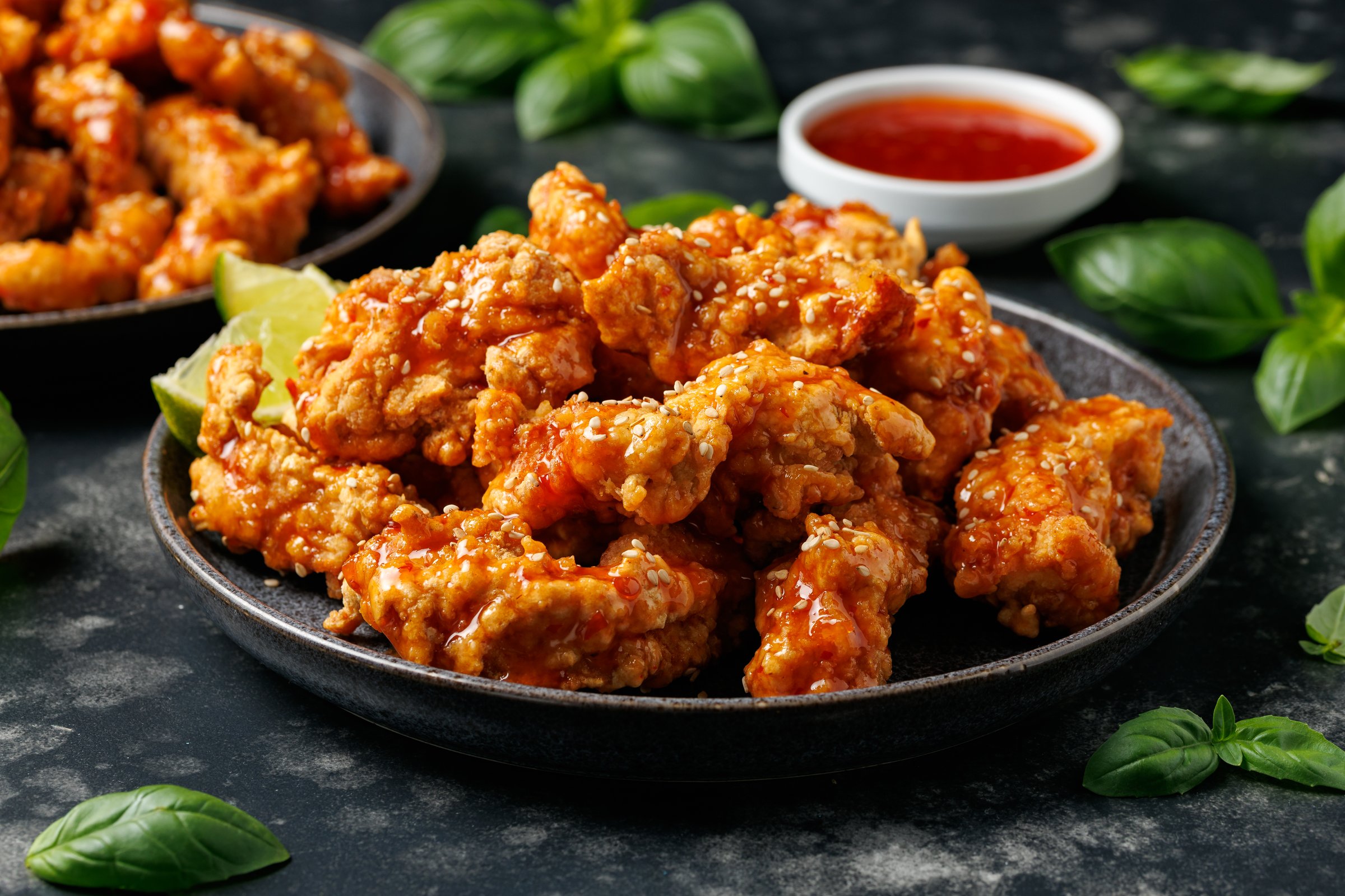 Korean fried chicken with spicy sauce and sesame seeds.