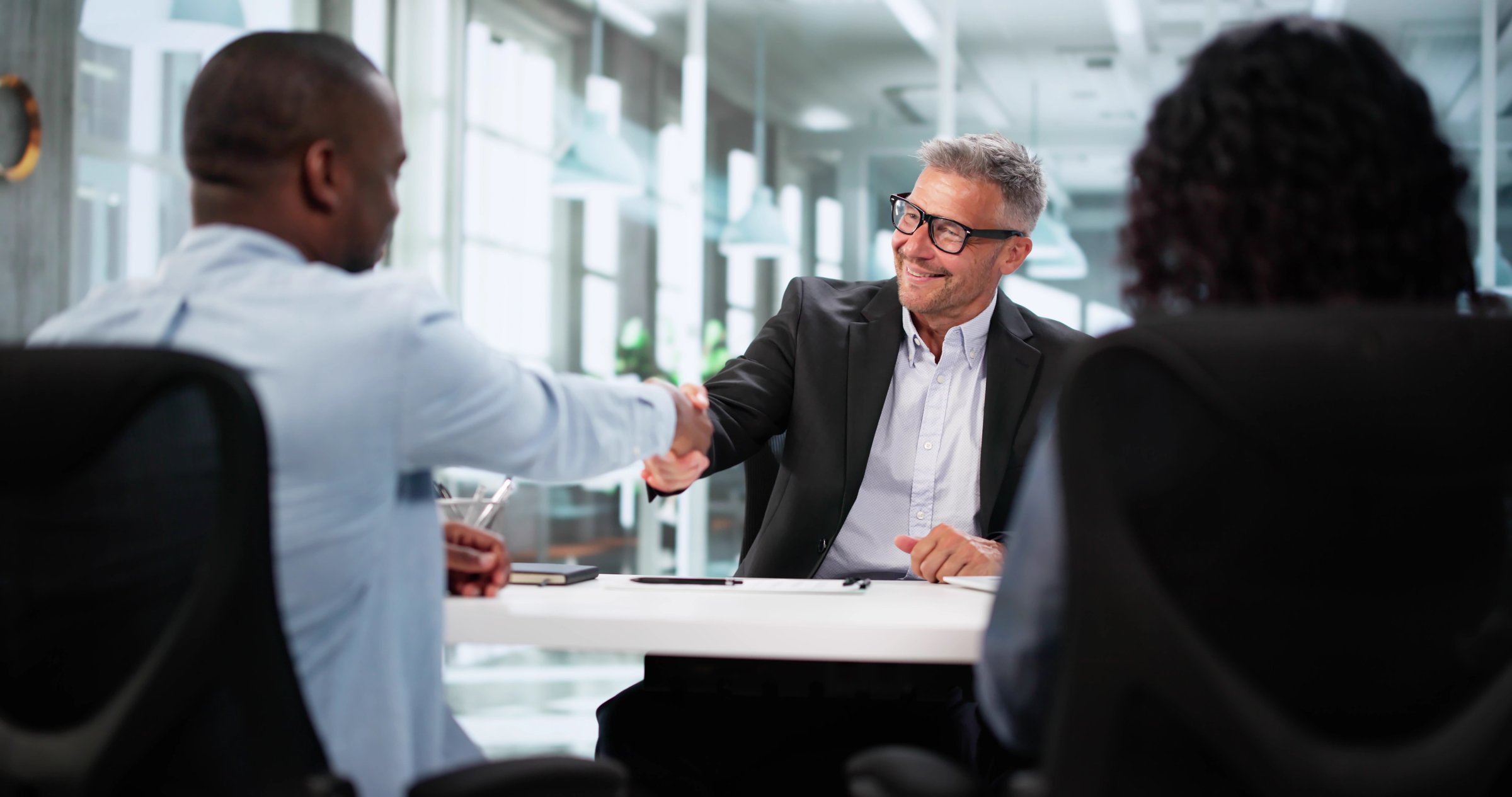 Happy Young Couple Meets Financial Advisor For Office Bank Consultation.