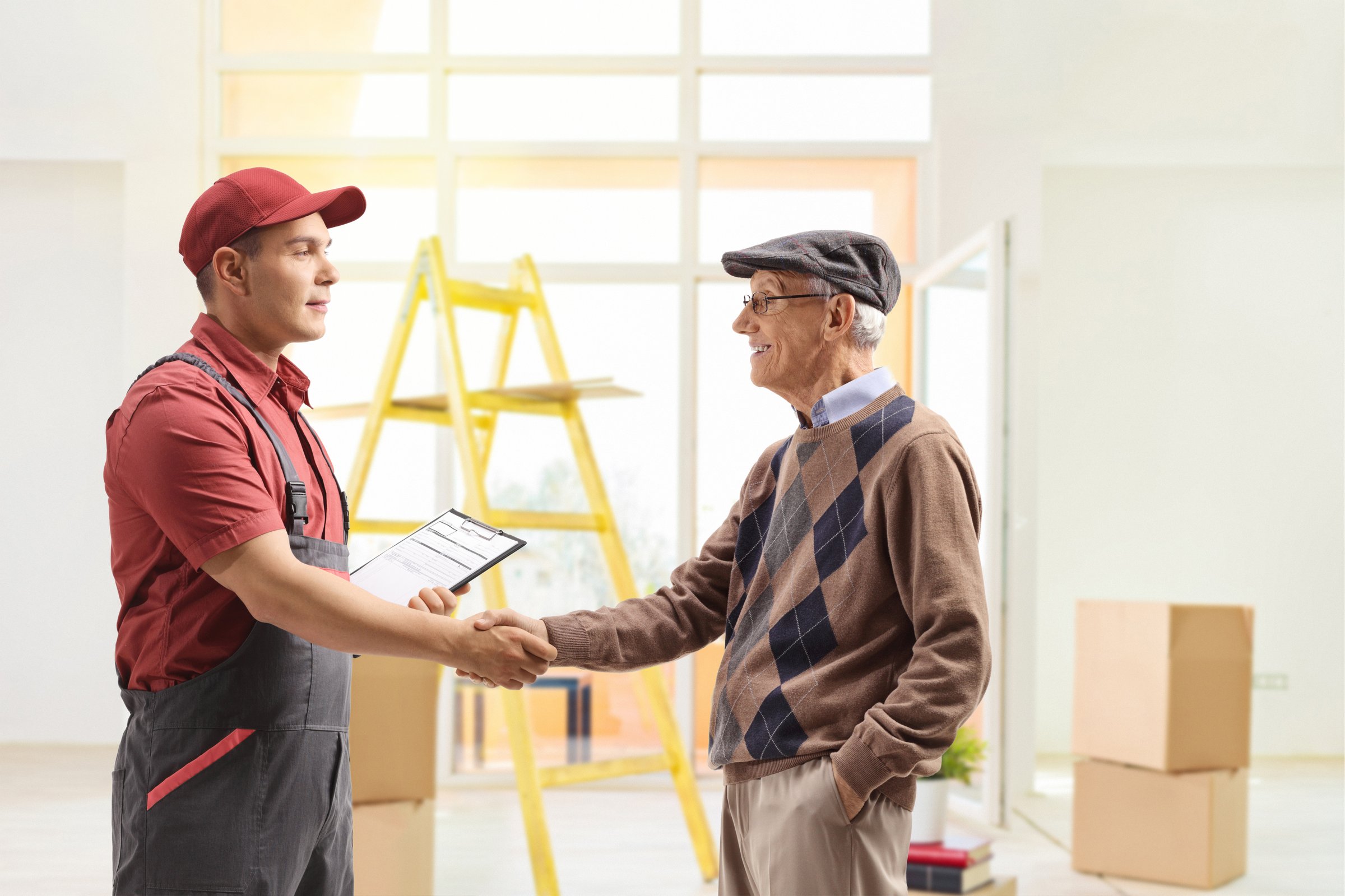 Mover shaking hands with a senior man inside a house