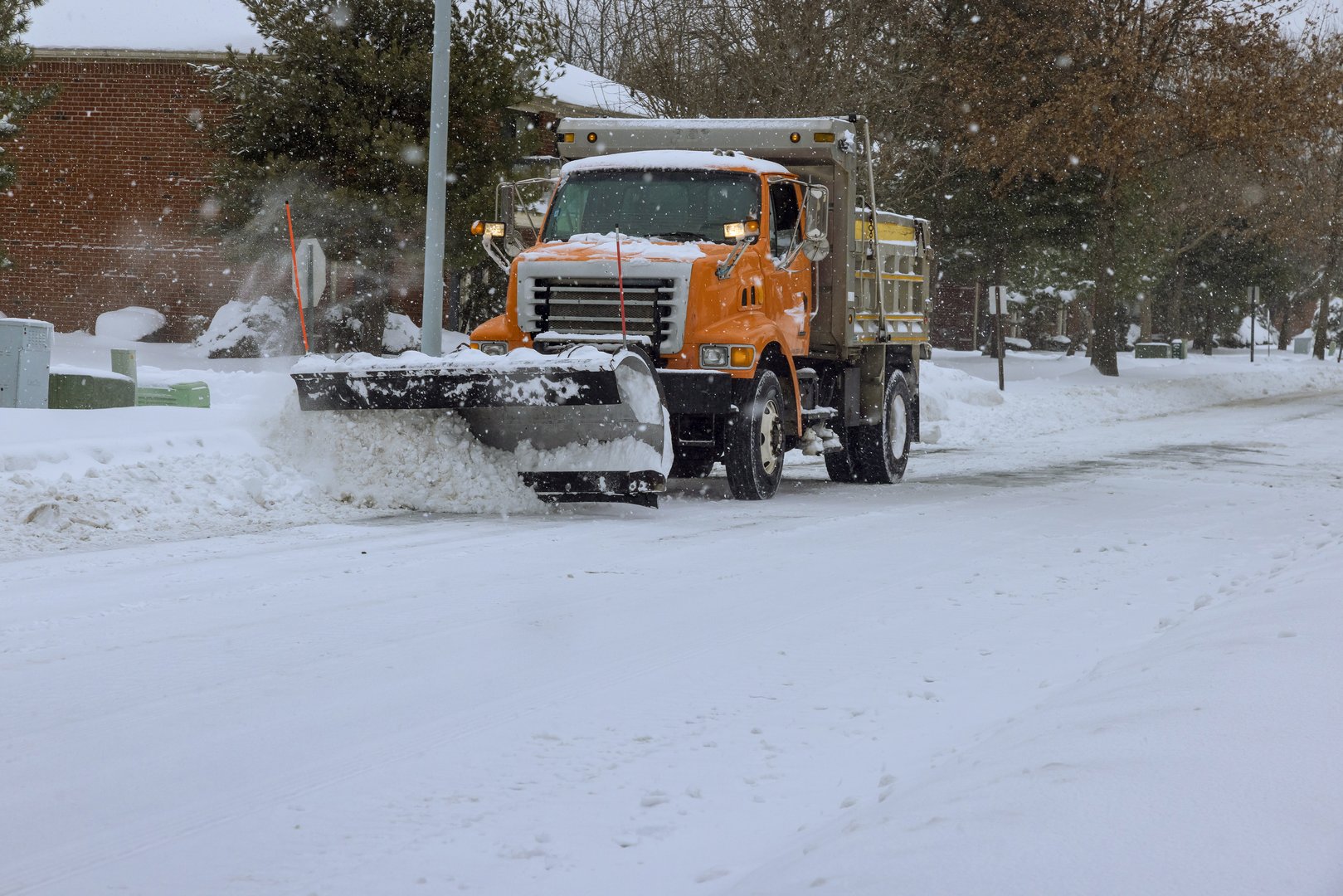 Snowplow truck removes snow from residential area during heavy snowfall