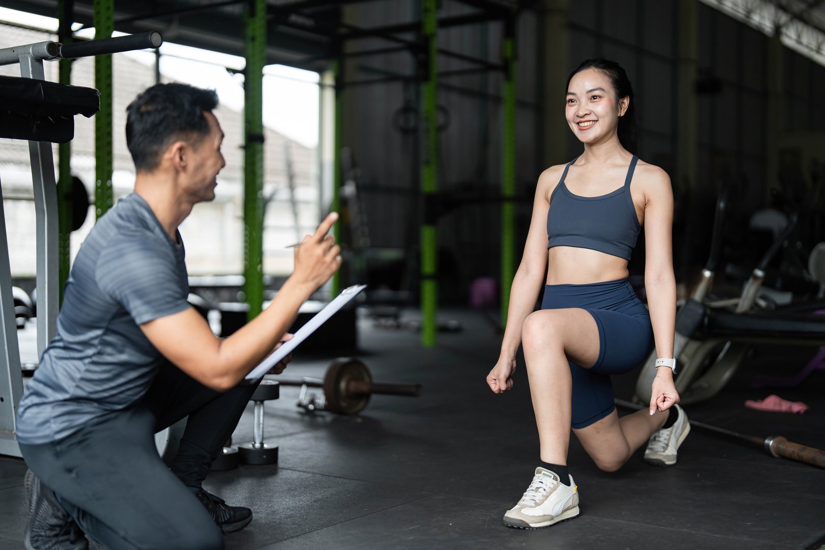 Personal trainer motivating woman doing lunges
