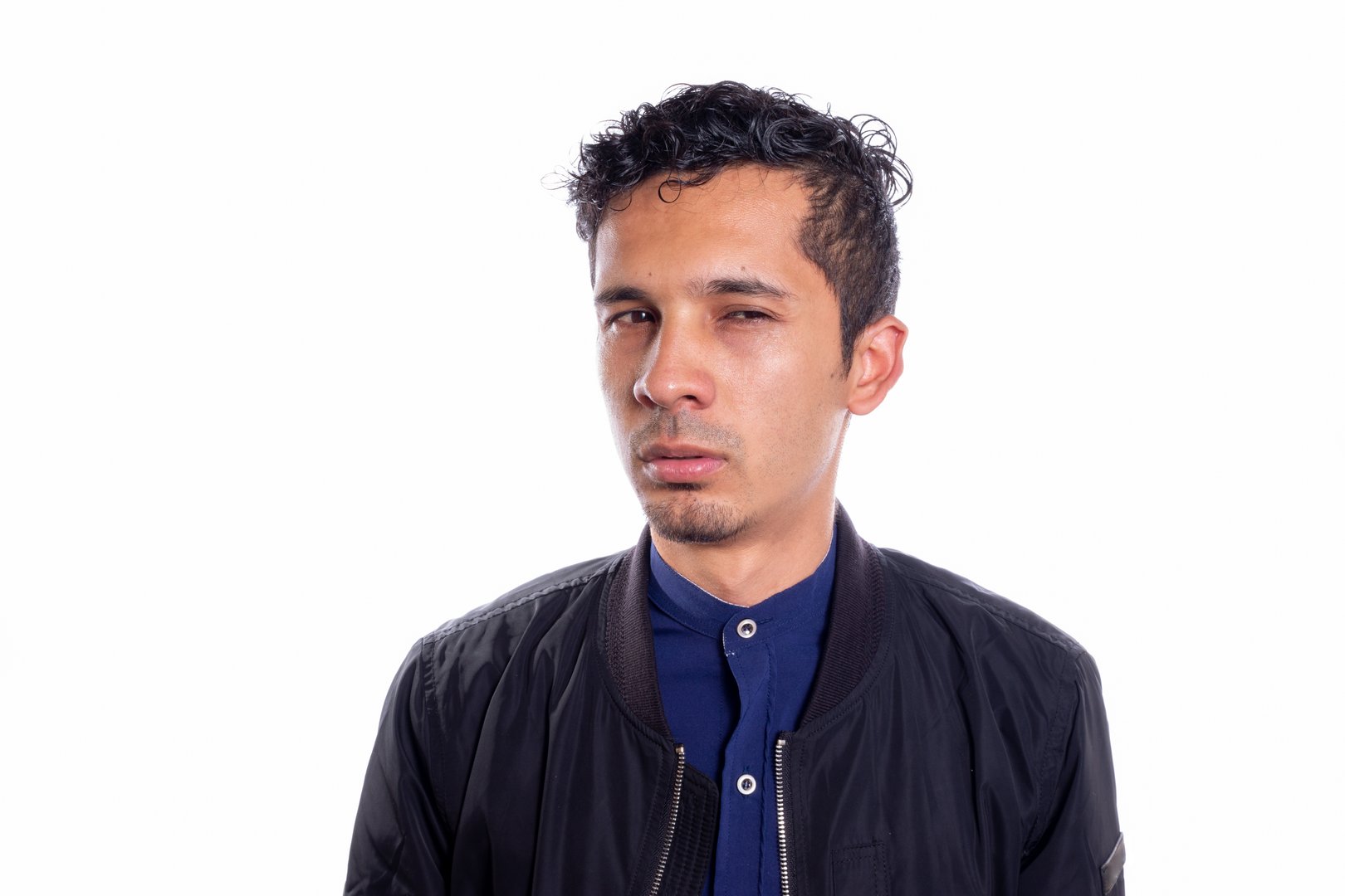Man with suspicious and doubtful look. White background. Young adult Latino young man suspicious of someone.