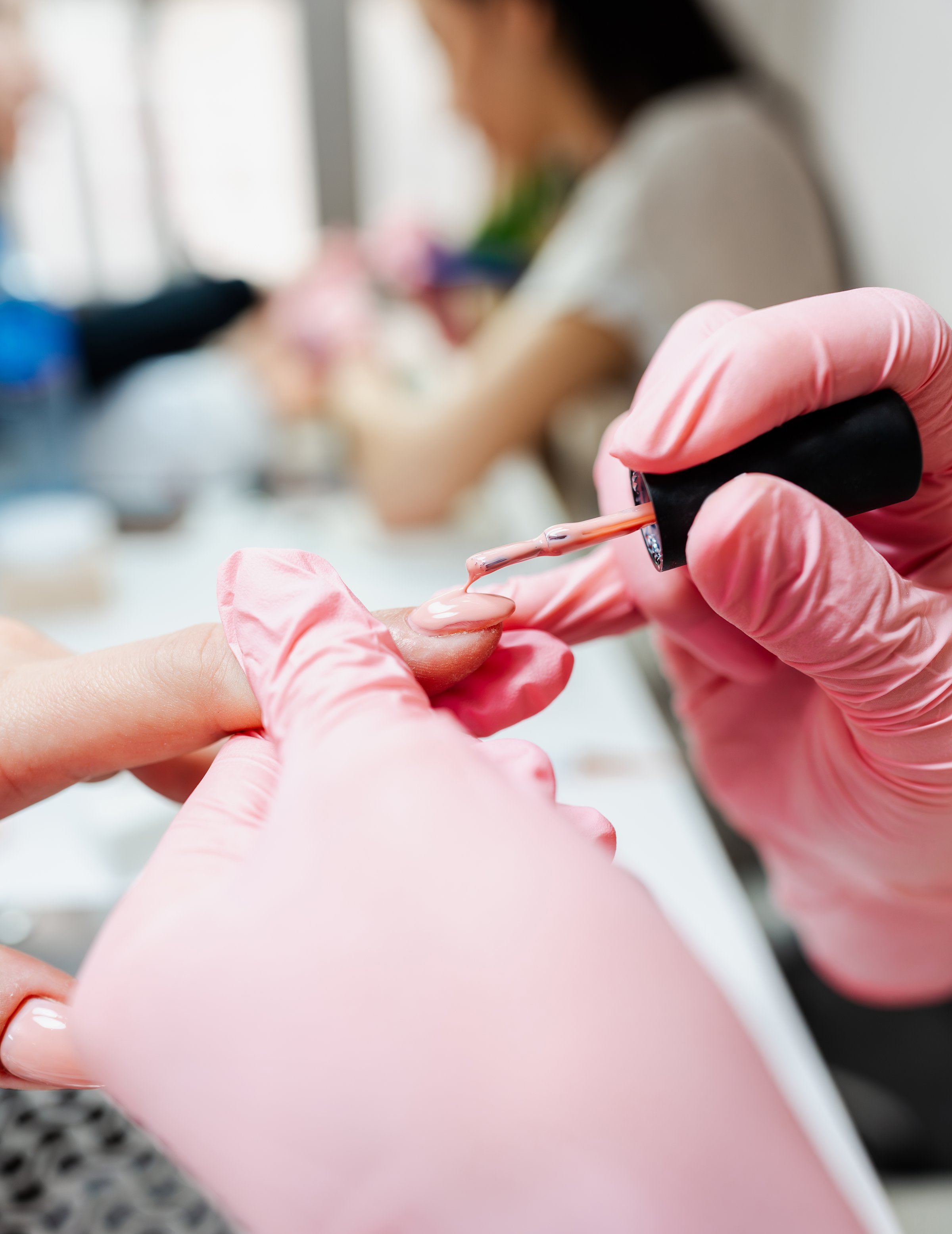 Professional manicurist working in a modern beauty salon. Satisfied female client receiving nail manicure treatments at spa center. Close up shot.