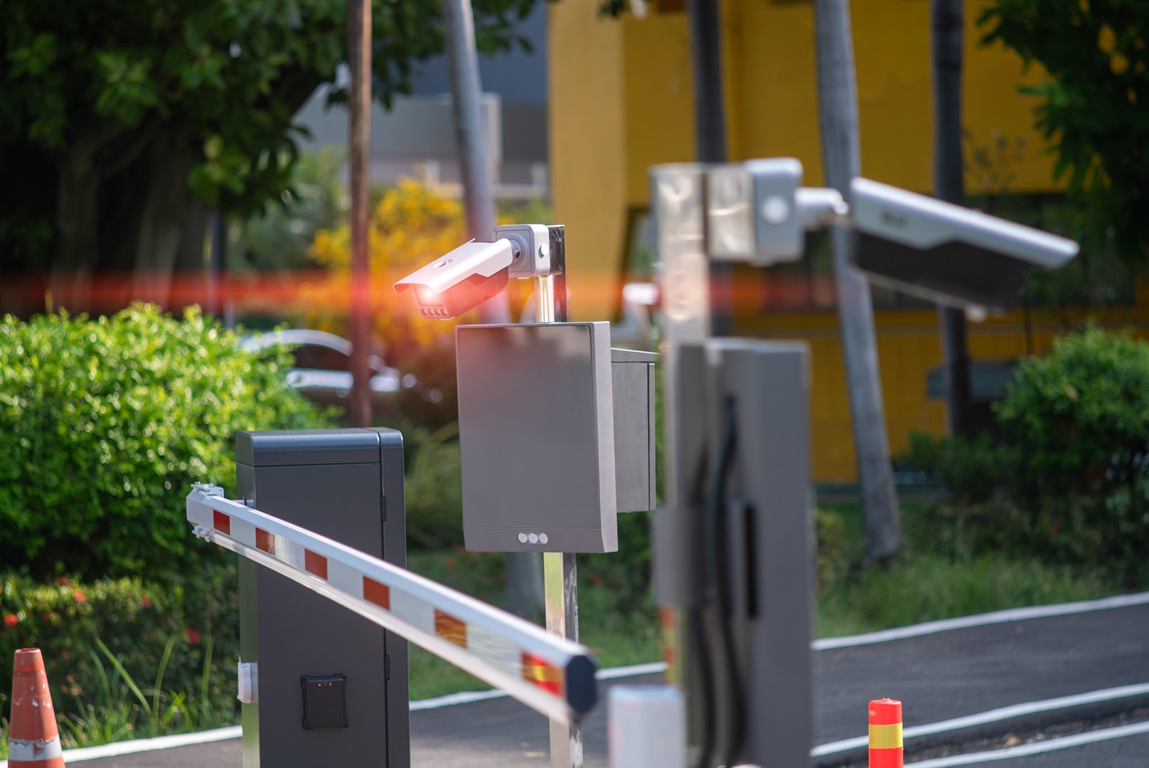This image features a modern access control system with a barrier and surveillance camera, providing security and monitoring for entrances in urban environments.