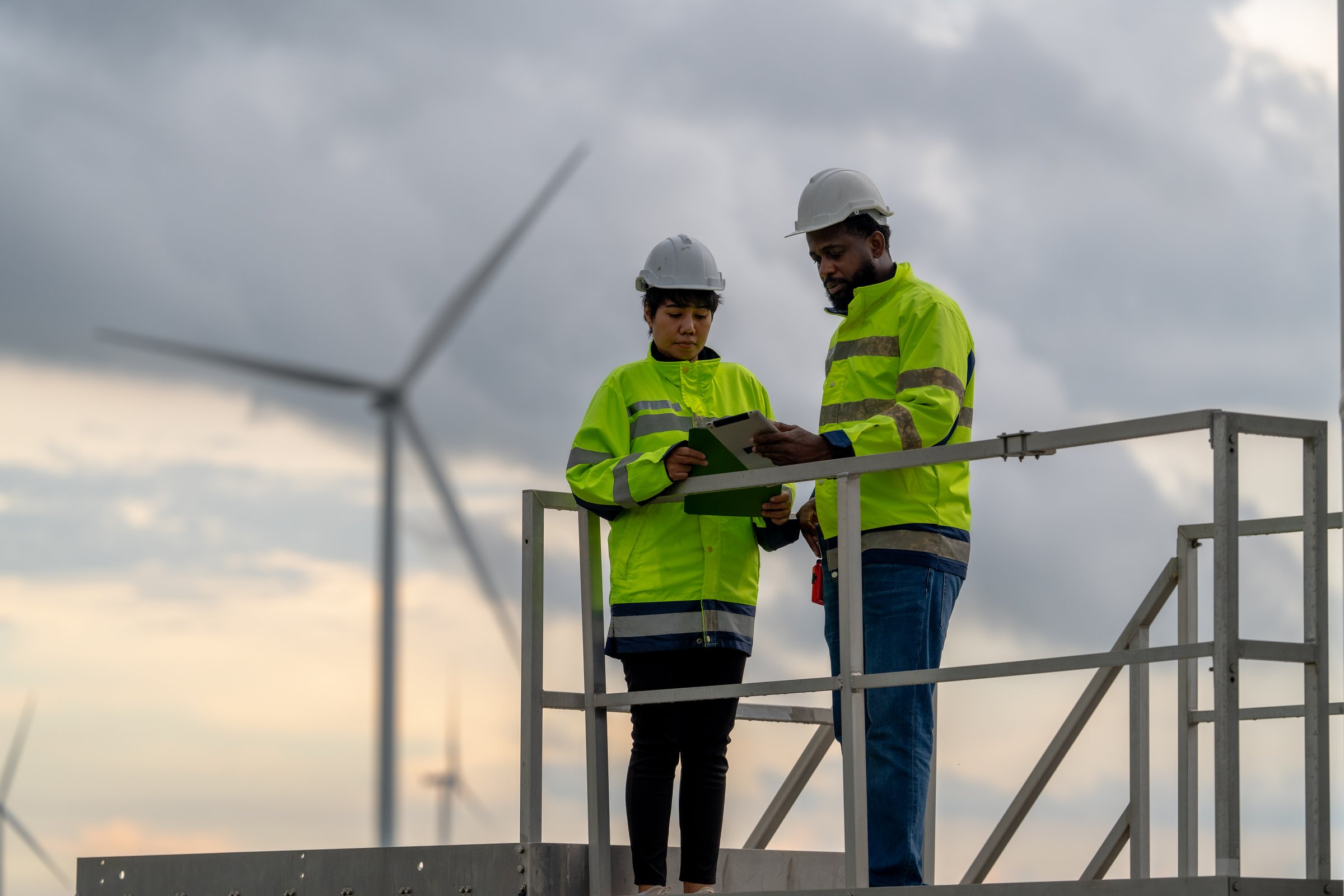 Shot of a two confident business persons talking in the work place. Two colleagues using a digital tablet while walking in a modern office. Businessman and businesswoman in meeting discussing business strategy. Business coworkers working together in the offic