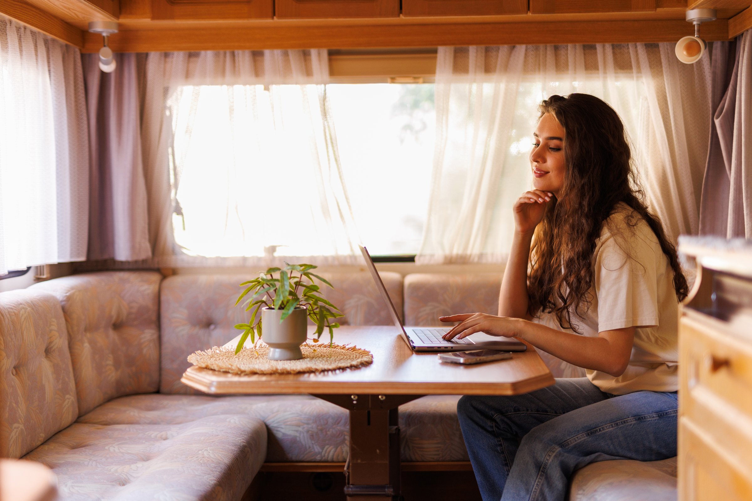 Young woman working on laptop in camper