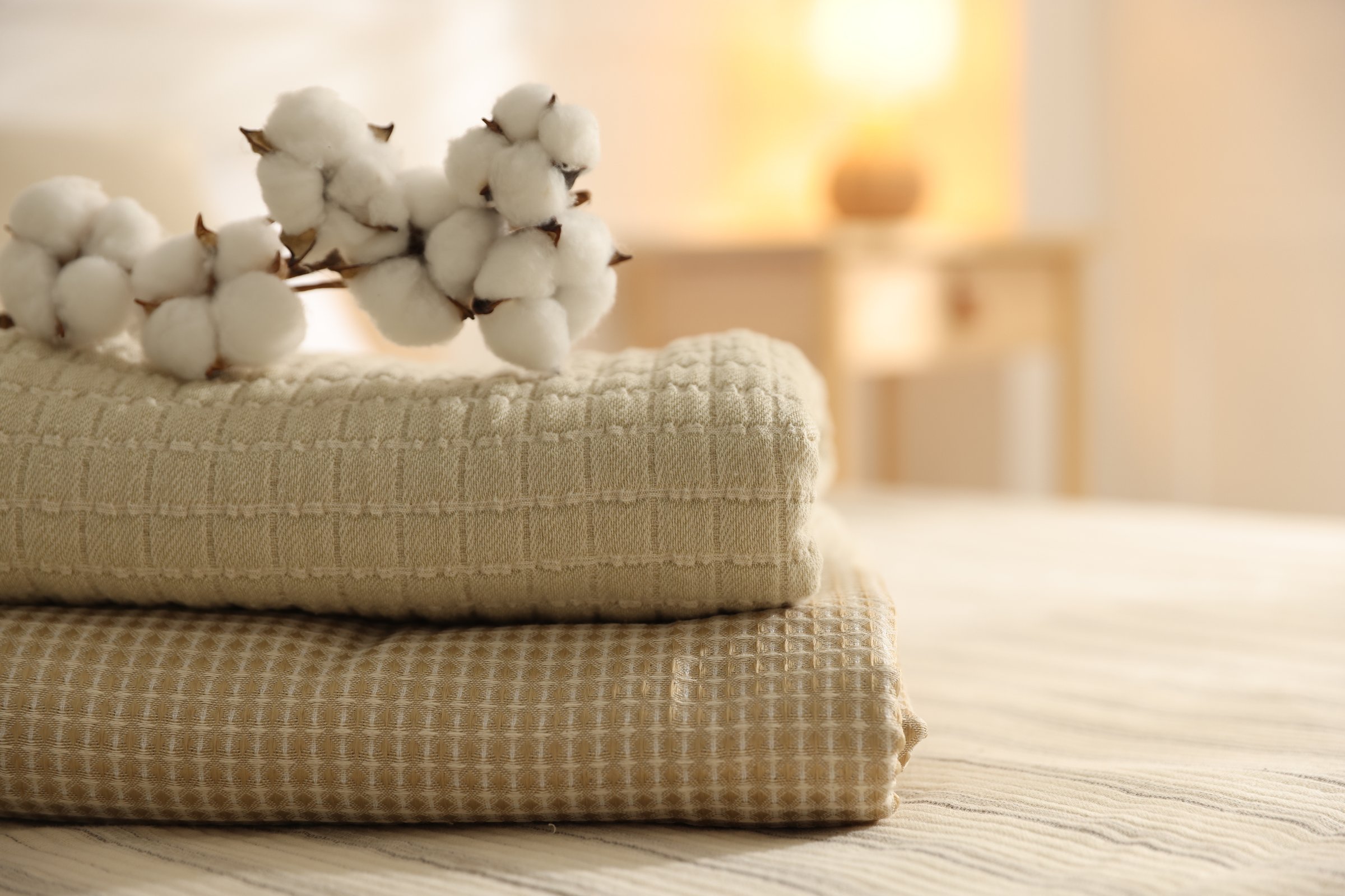 Stack of clean towels and cotton flowers on bed