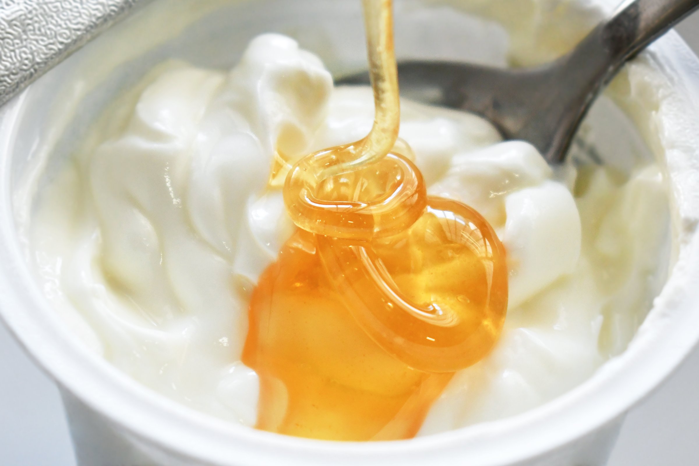 Pouring honey syrup on greek yogurt pot. Healthy and dietary food.