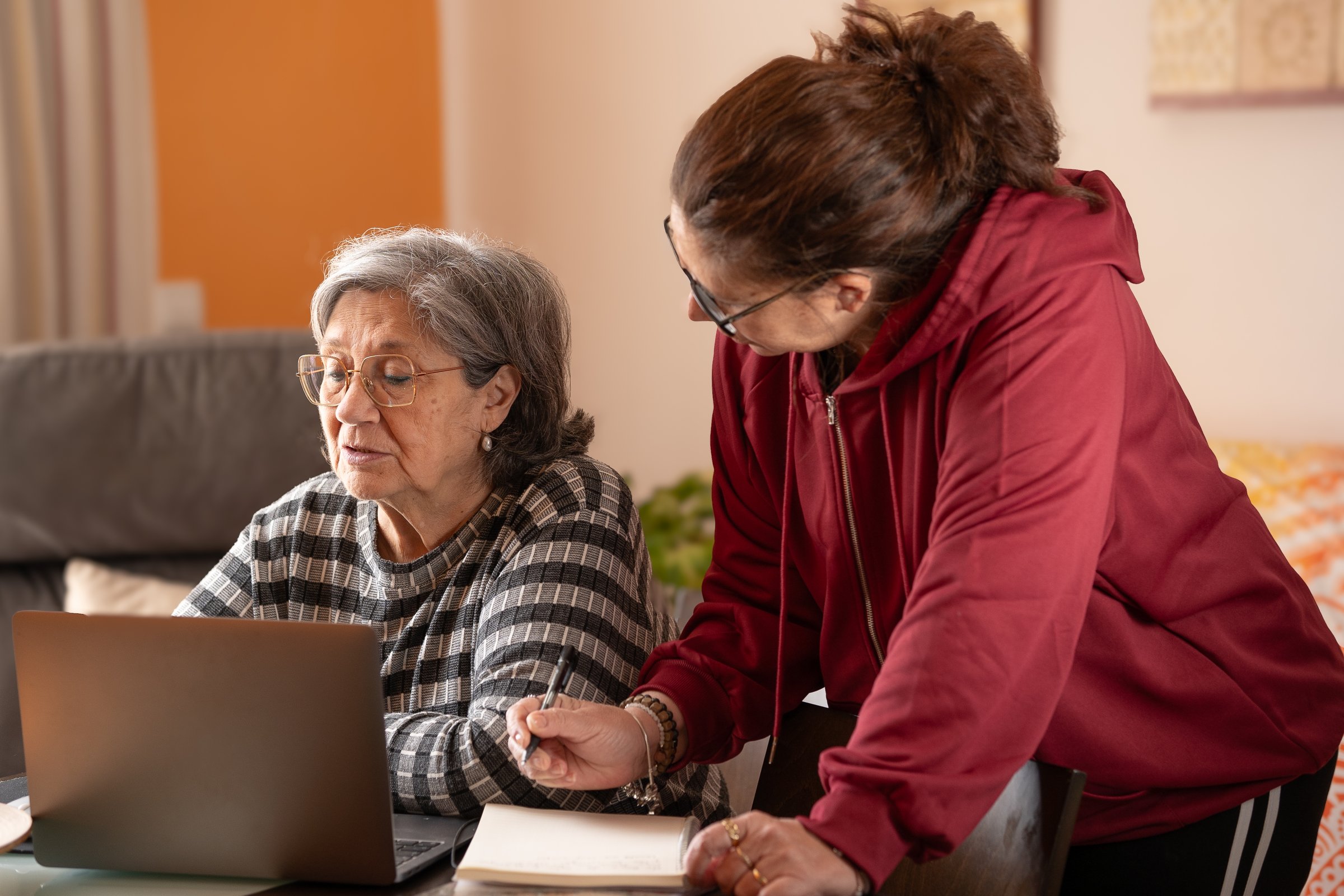 woman taking notes while her mother is at the computer
