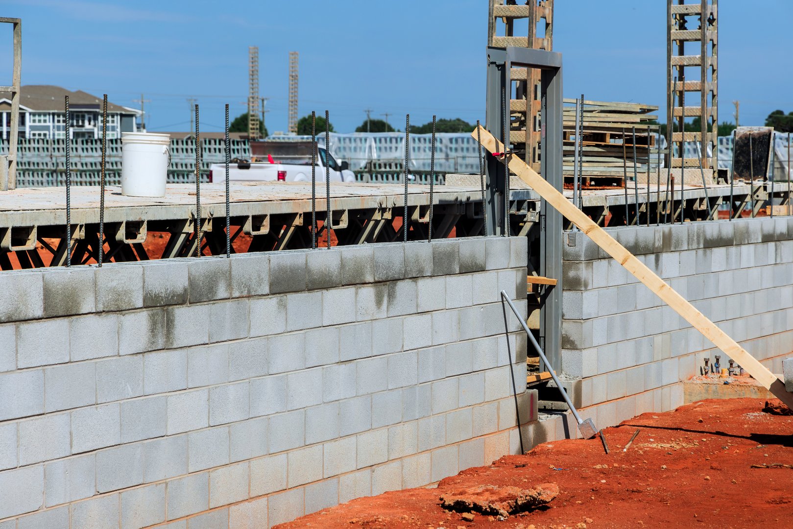 Workers are constructing masonry wall at construction site with materials arranged for ongoing building efforts.