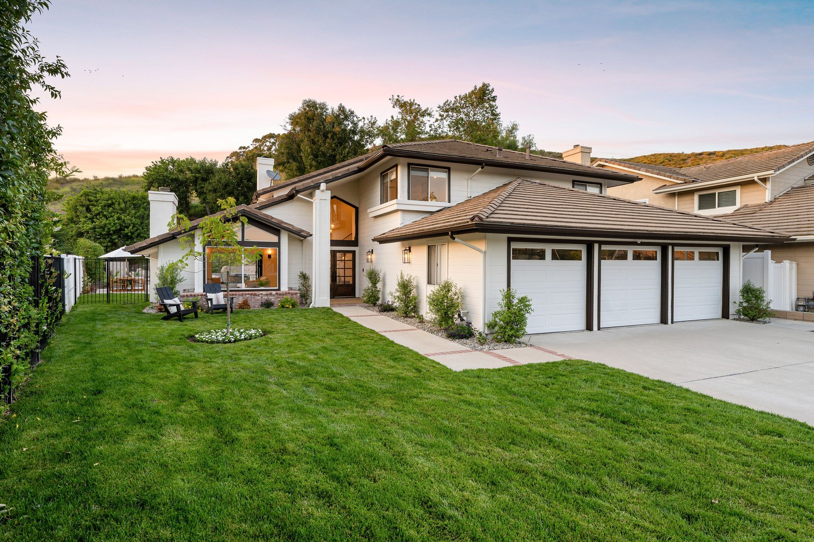Modern suburban house with a well-maintained lawn and a three-car garage at sunset