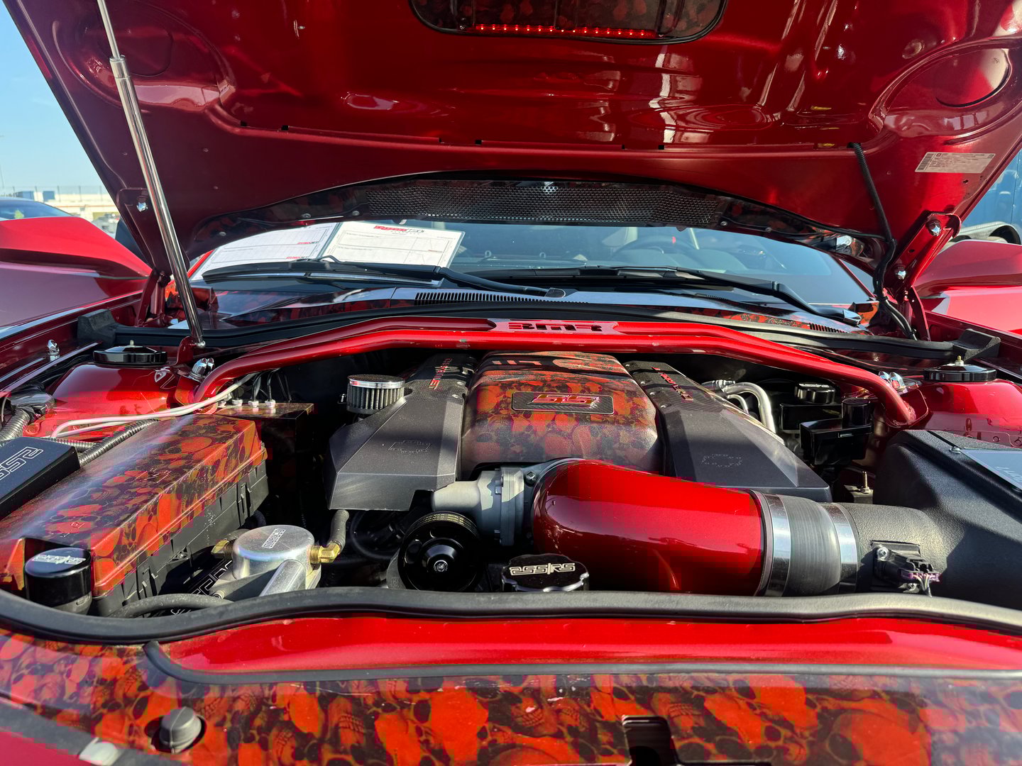 A distinctive engine bay of a striking red car displays intricate detailing and modifications, observed in Nashville, TN, USA on October 12, 2024, highlighting automotive craftsmanship.