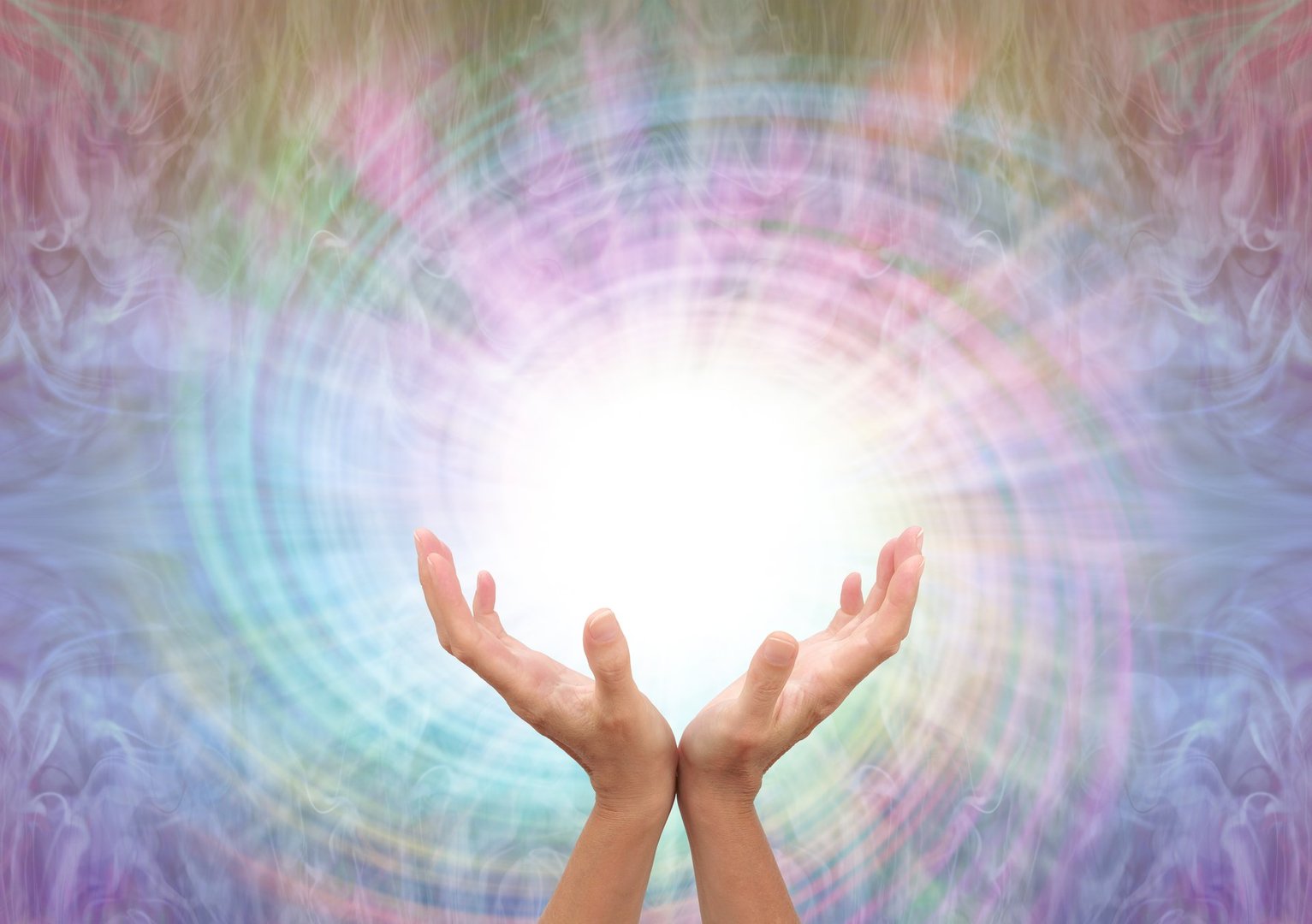 female cupped hands reaching up into a white vortex energy against a multicoloured  spiralling light background with copy space
