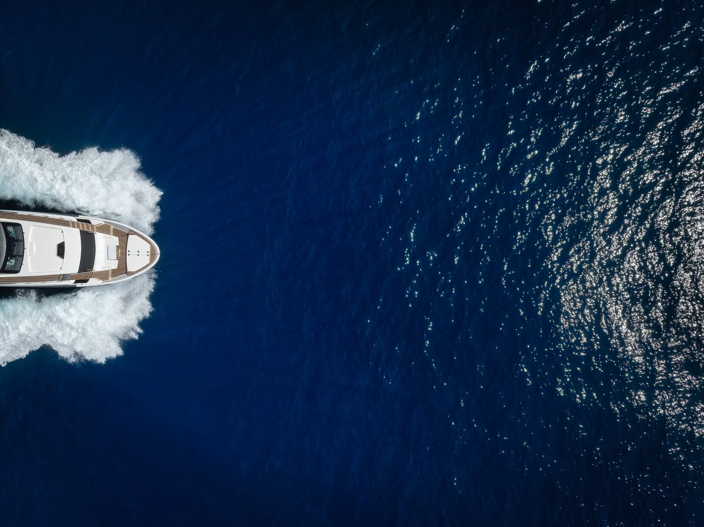 Aerial overhead close up view of a bow of a luxury yacht sailing with high speed over the ocean with copy space