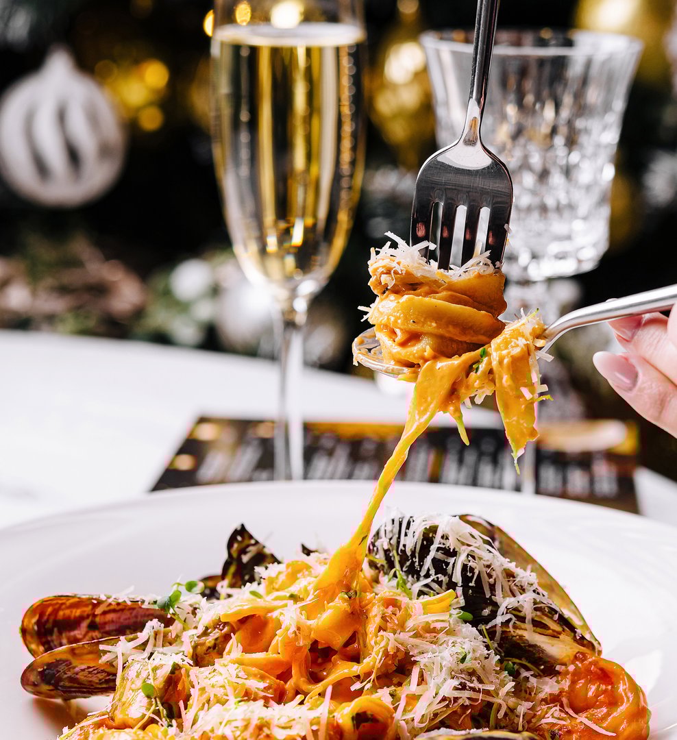 Close-up of a fork twirling a delicious pasta with seafood garnished with cheese