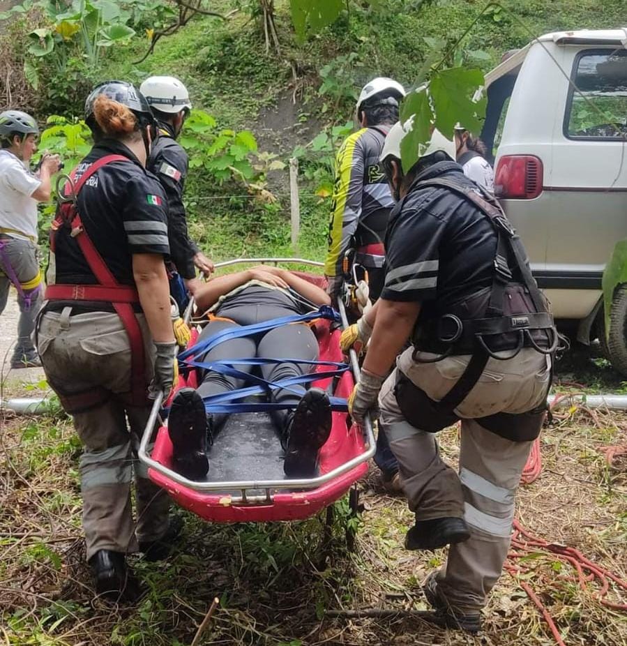 Rescue team carrying a person on a stretcher near a van in a wooded area.