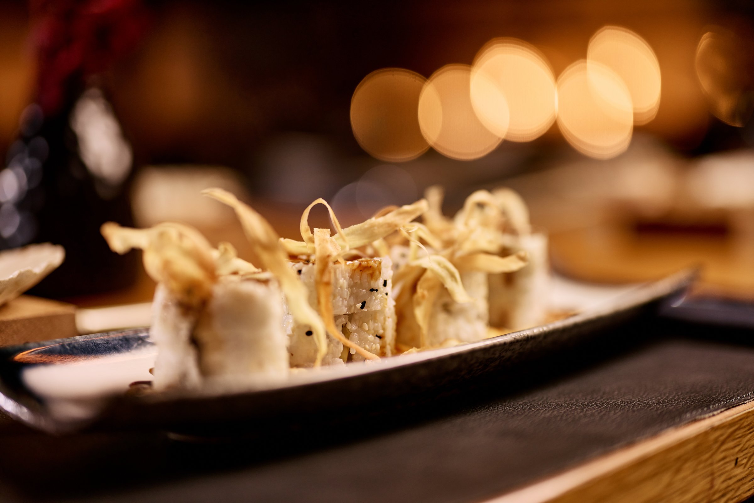 Gourmet sushi rolls garnished with crispy topping served on an elegant plate.