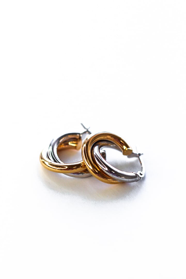 Gold and silver interwoven hoop earrings on a white background.