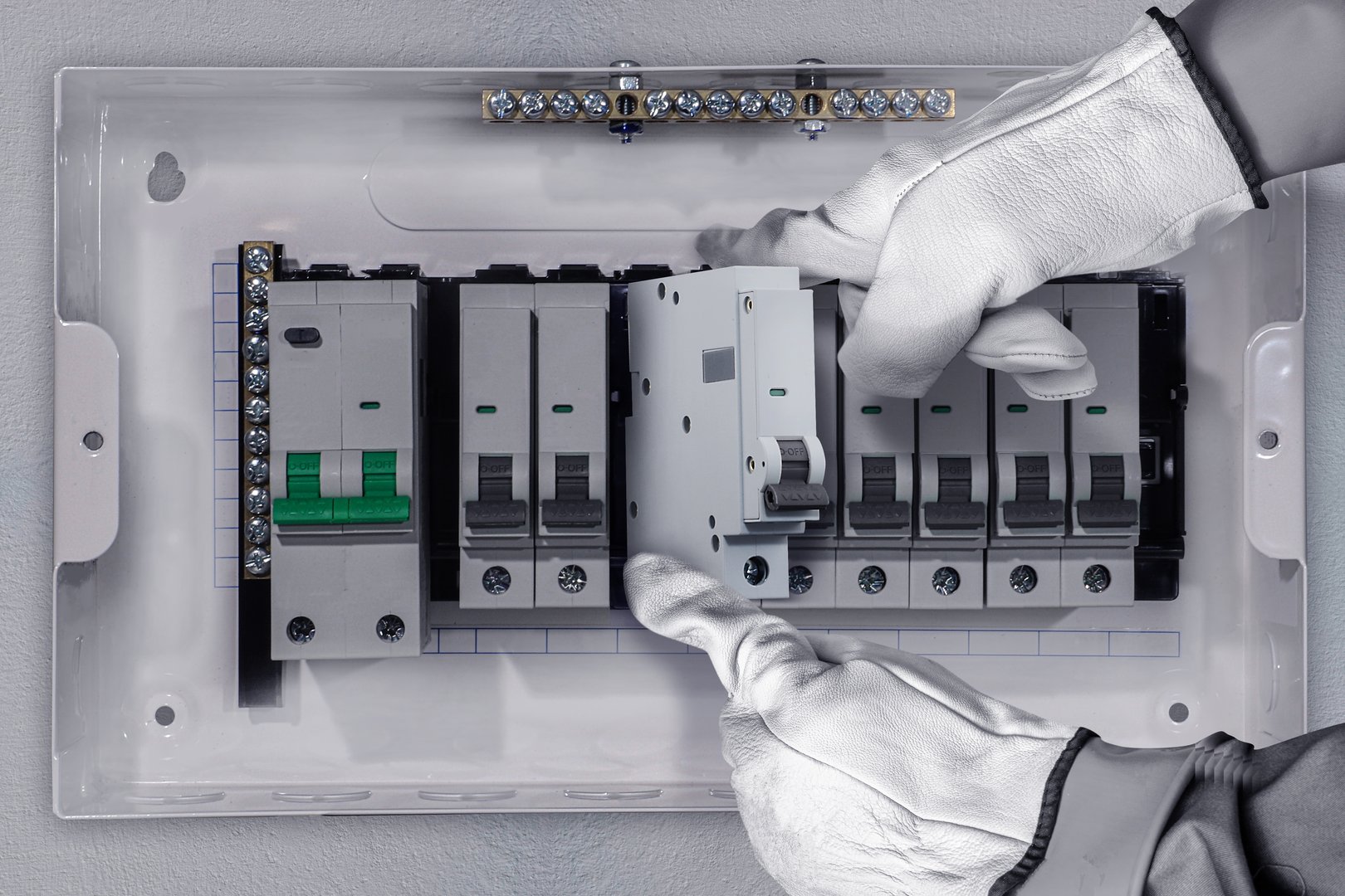 Professional electrician working on breaker panel with tools