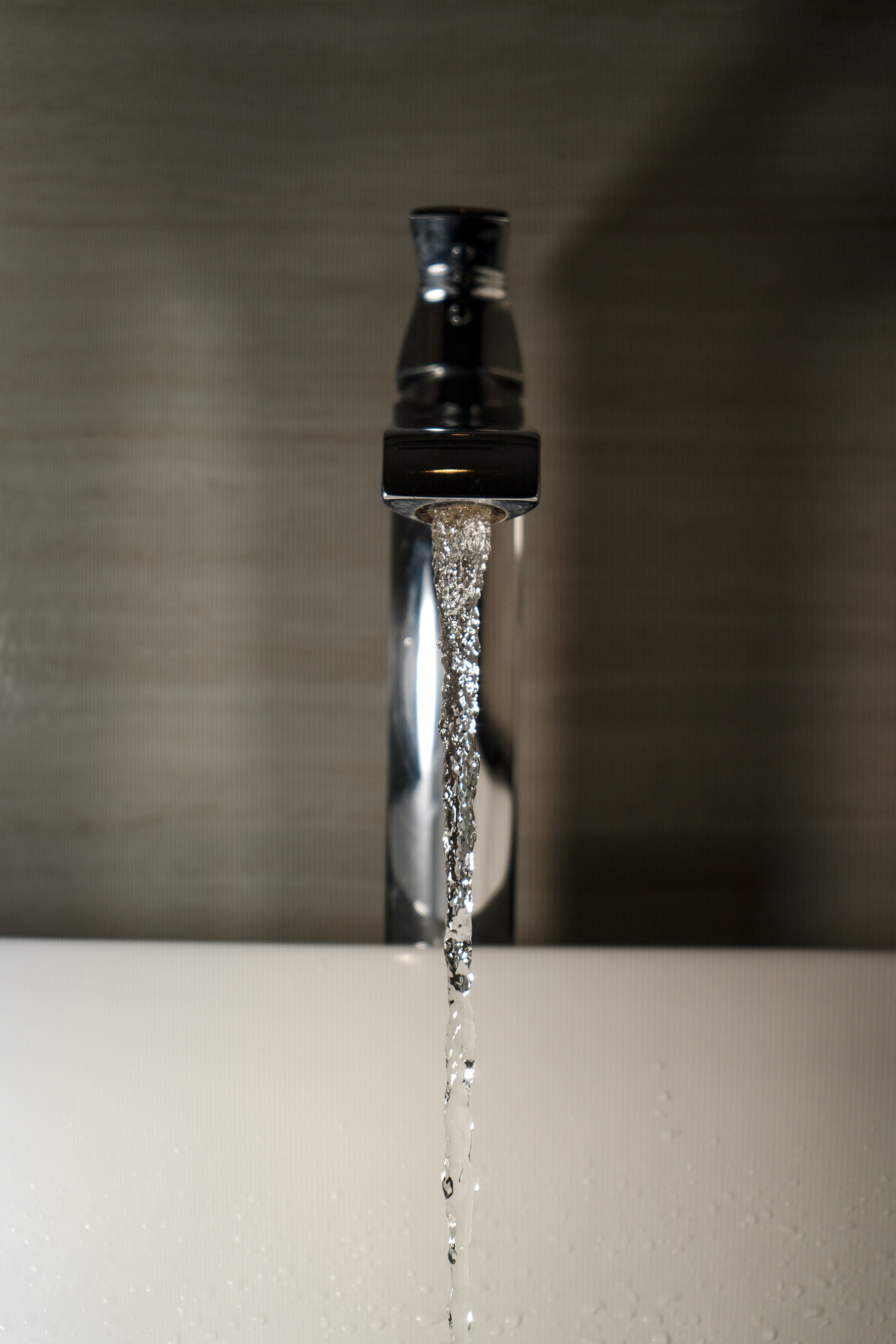 Shiny faucet with water flowing in a clean bathroom sink